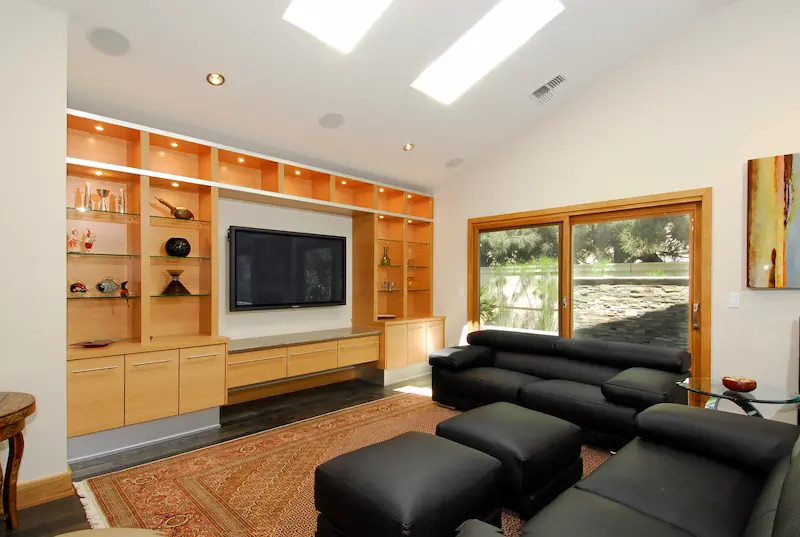 Close-up of modern living room with yellow built-ing cabinets, black leather couches and skylights in the ceiling. Irvine Transitional Modern Project. Photo by Chris Darnall.