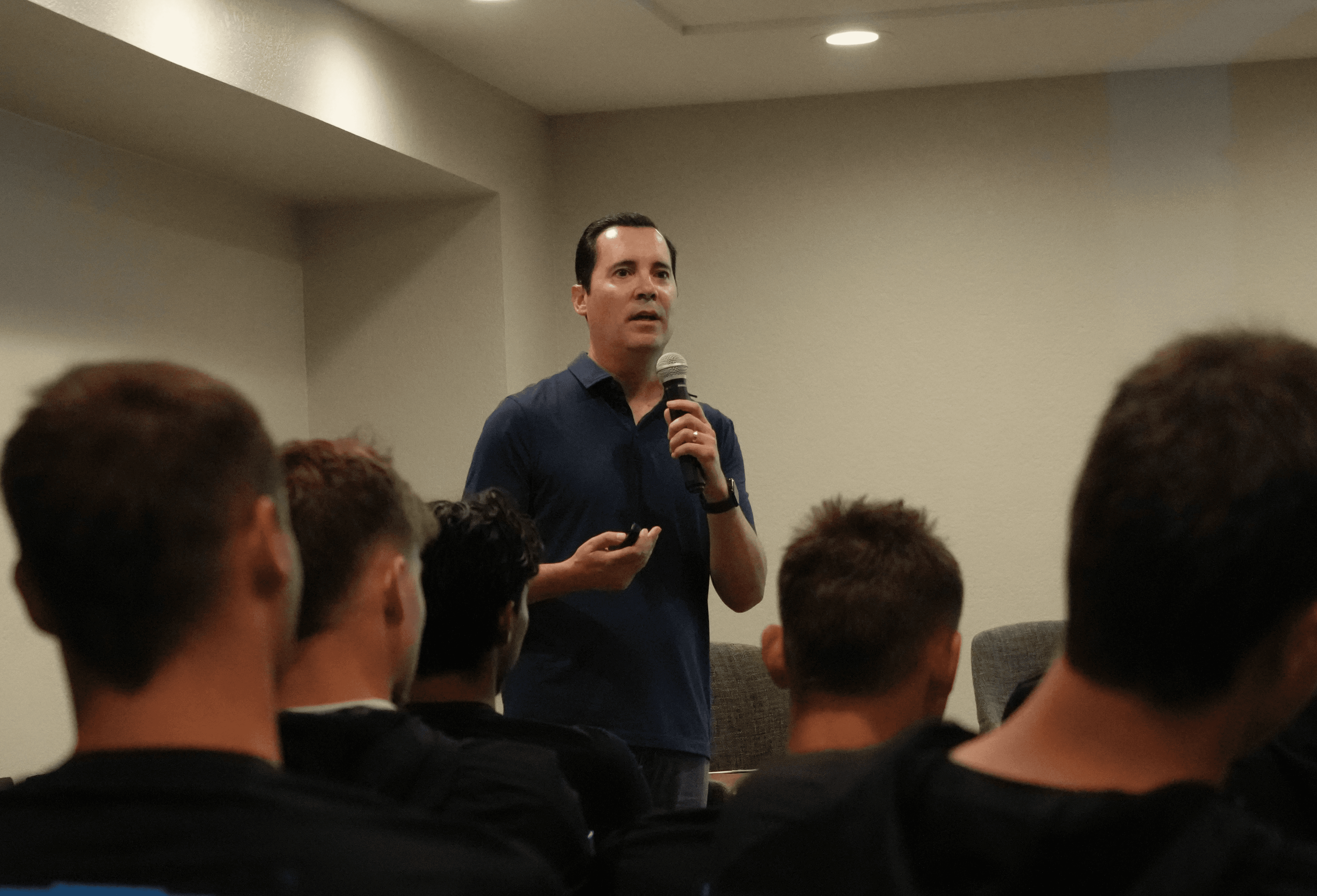 A man speaking into a microphone to young athletes