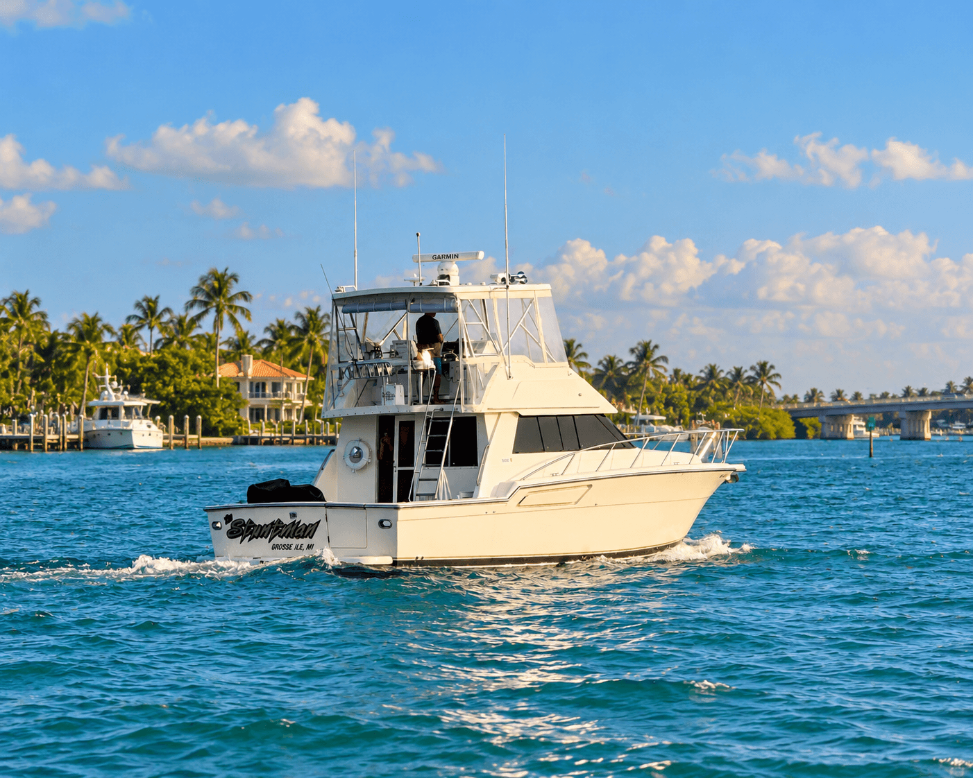 Stuntman, Tom's sportfish yacht from Grosse Ile, Michigan, running a Florida waterway past palm trees, waterfront homes and a bridge