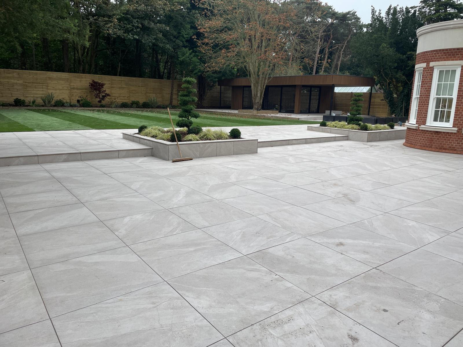 Luxury Landscape Transformation in Cheshire by LK Landscaping and Groundworks - Large-format natural stone patio, raised beds, and lush greenery create an inviting outdoor oasis. Expert hardscaping and landscaping services for high-end residential properties in Cheshire