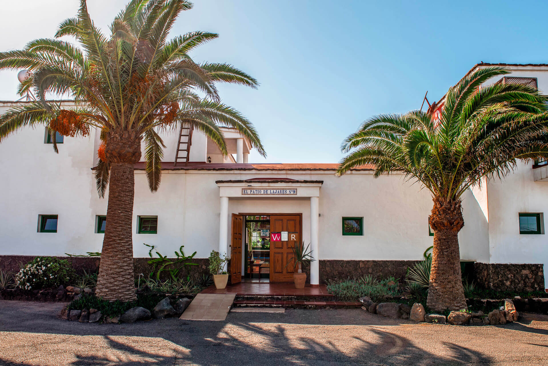 Edificio blanco con palmeras y puertas abiertas