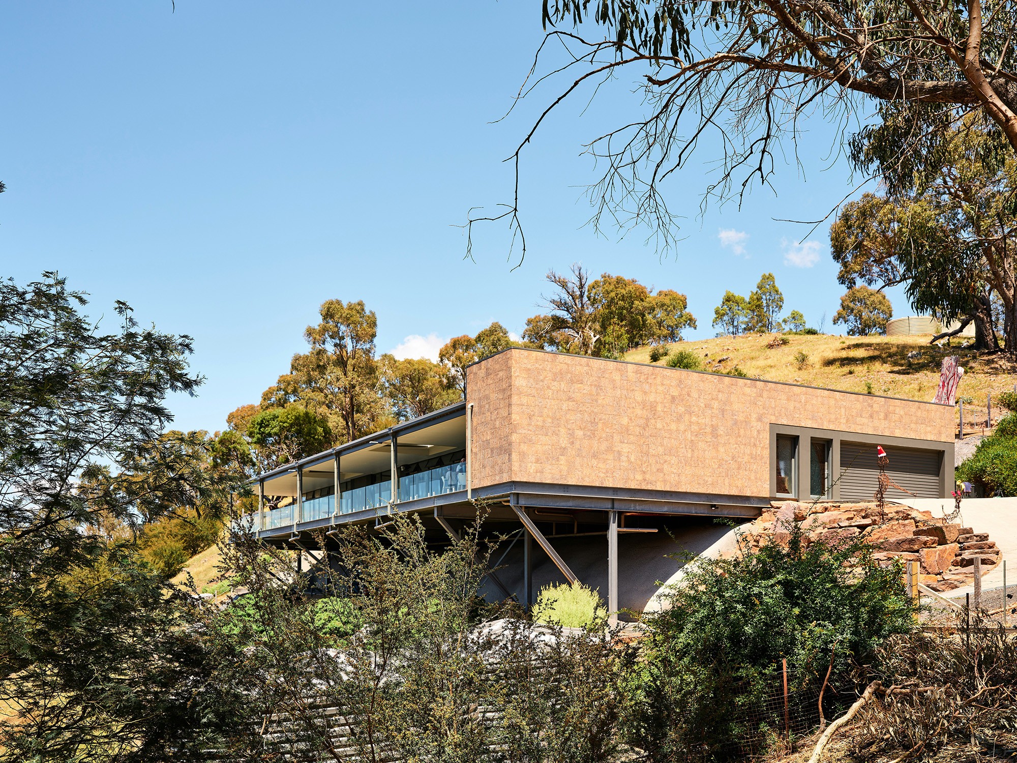 Modern hillside house with stilts and glass railing