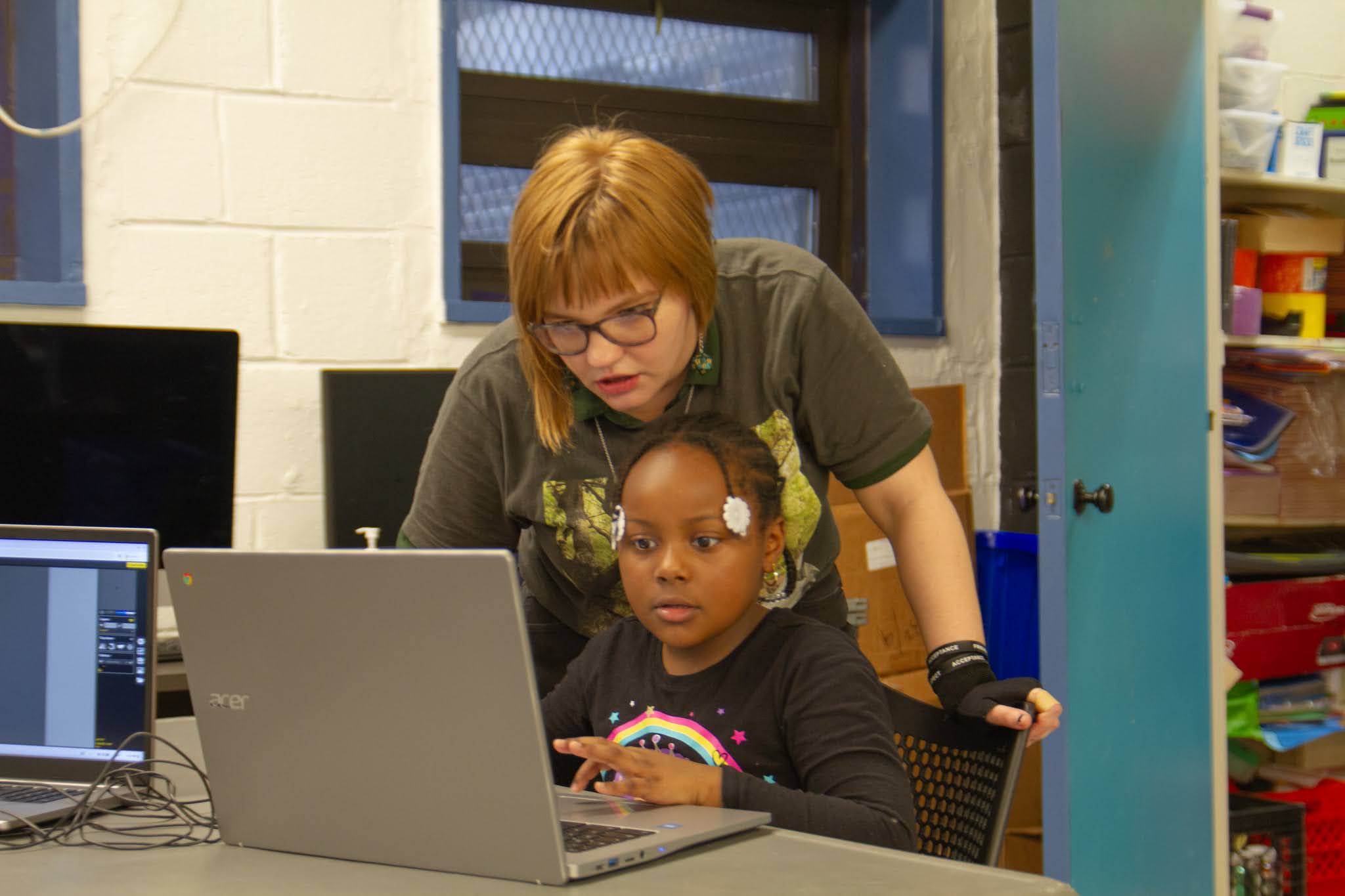 An adult helps a young child learn how to use a laptop