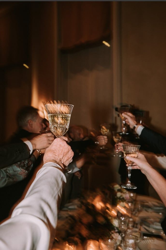 A couple dances closely, showcasing a flowing green dress, against a soft, blurred background of other guests.