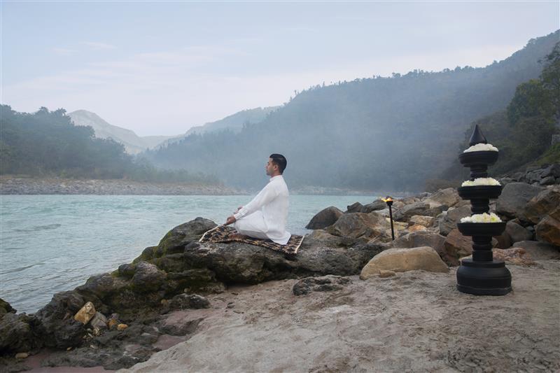 Man meditating near river bank