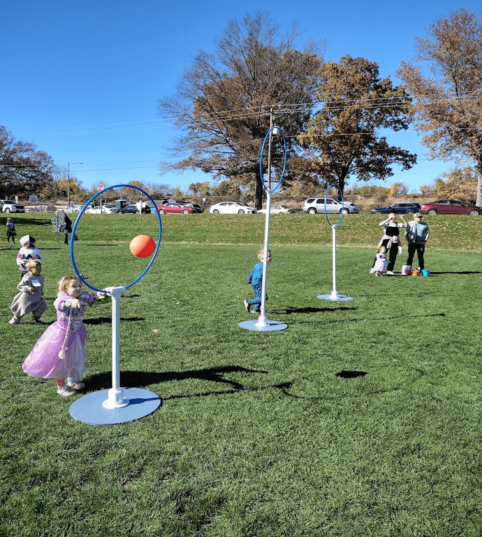 A child in a princess dress launches a ball into the small hoop