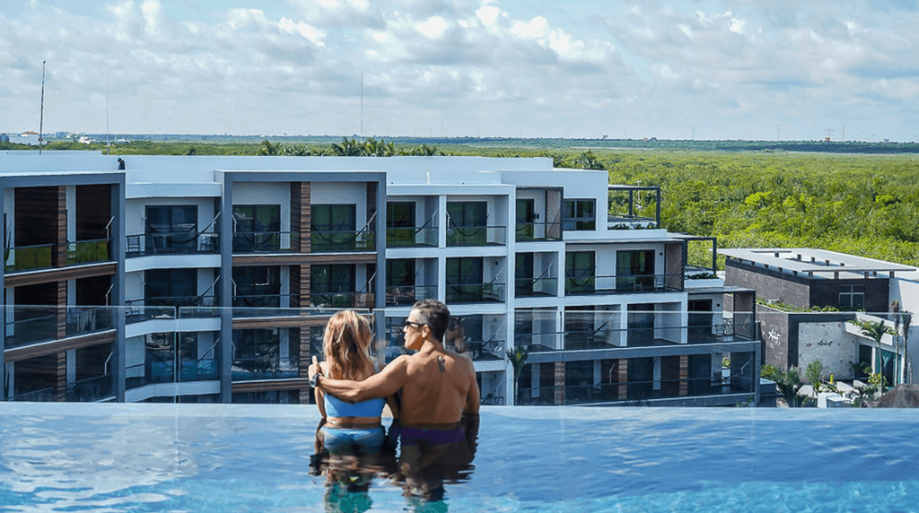 Couple standing on a balcony with binoculars in hand looking out over the ocean