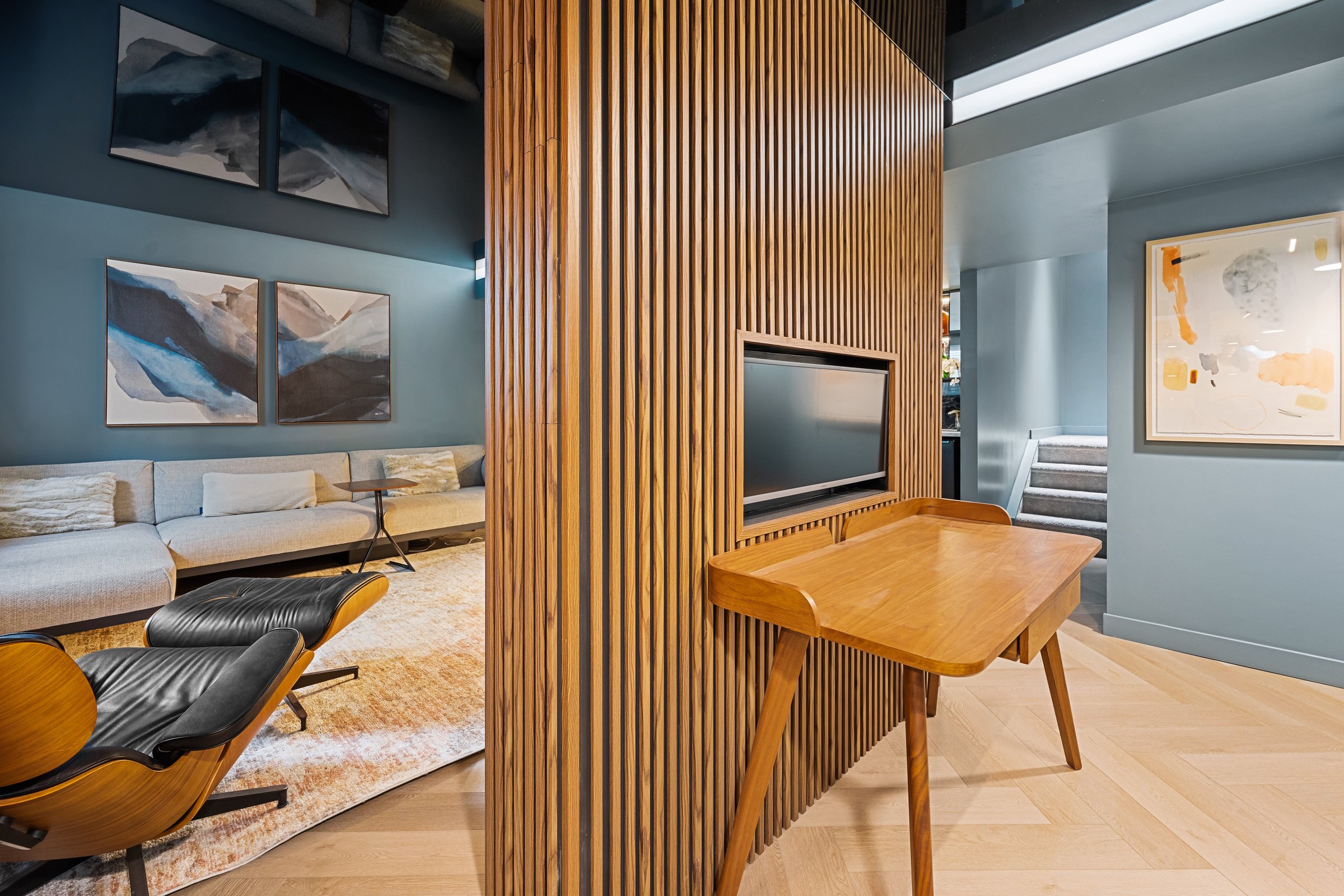 Crestmont basement finished: slatted divider with desk and screen, family room sofa and the stair beyond