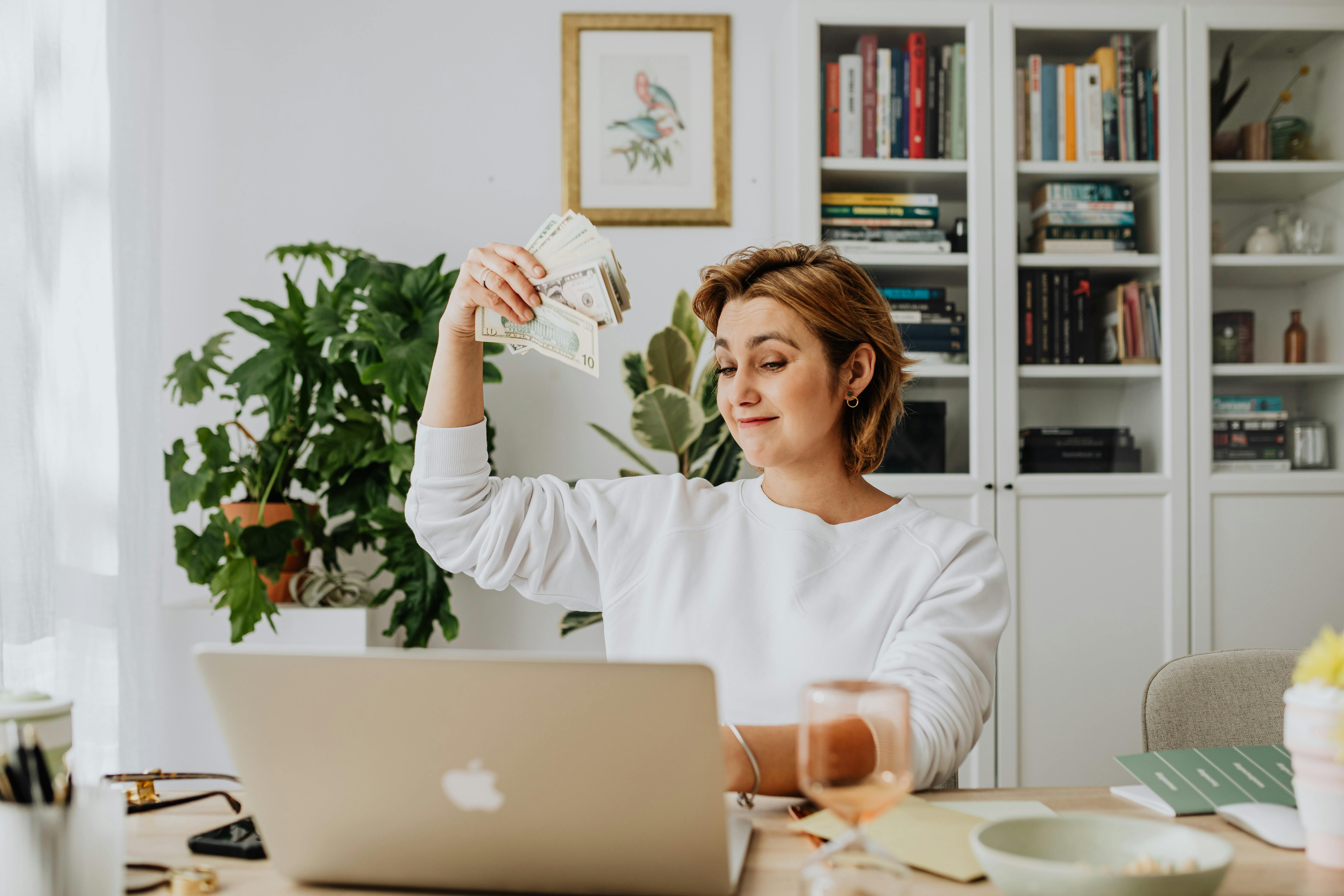 Mortgage agent in front of a laptop and waving cash