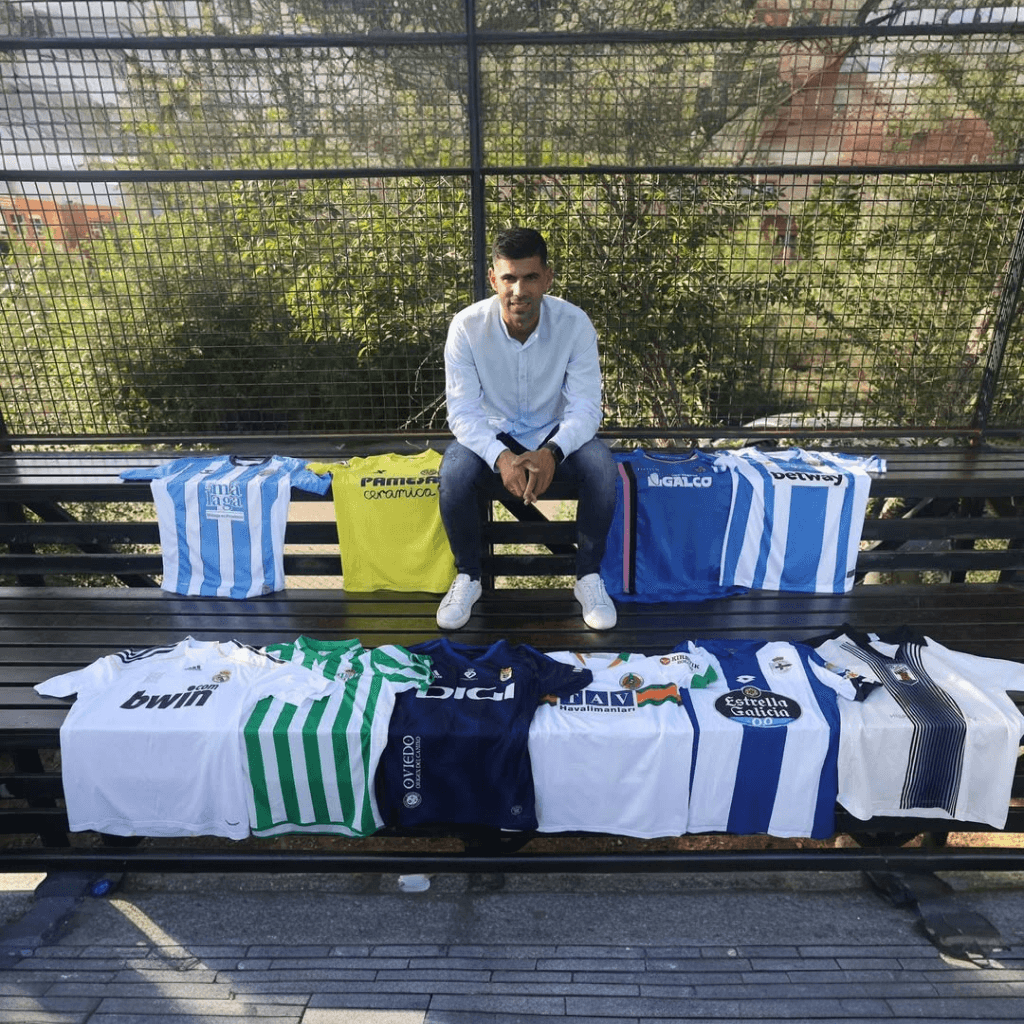 Hombre joven sentado junto a camisetas de futbol