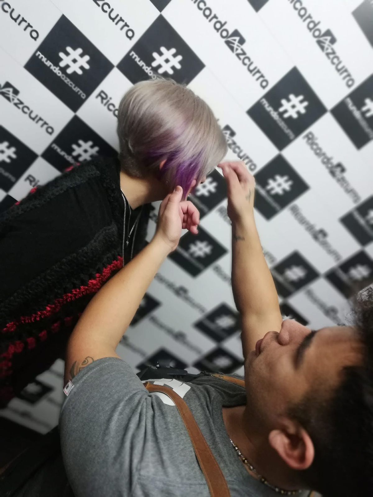 A stylist is doing a client's hair at the Camelia beauty salon. In one hand, they hold a hairdryer, and with the other hand, they adjust the hair.