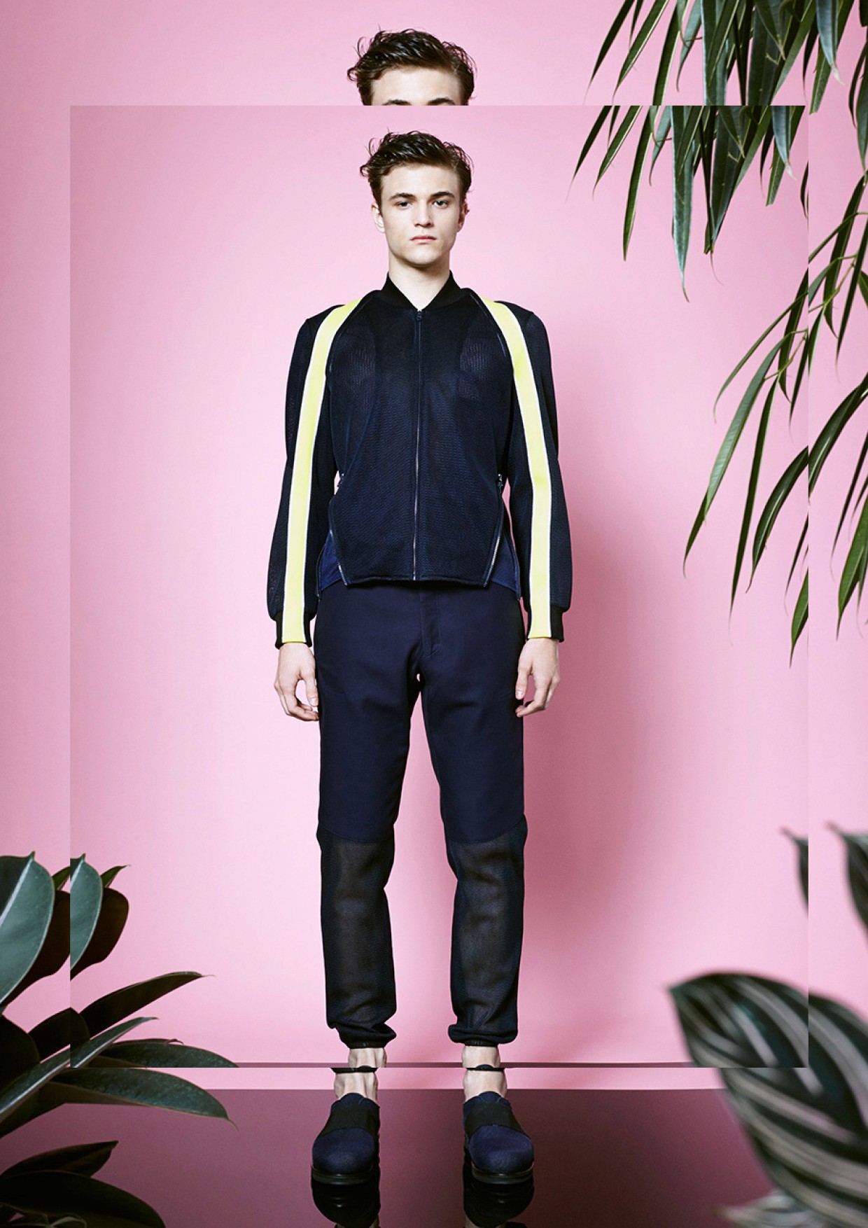 A blong young lady who has a short hair wearing a dark blue knitted jumper. On her sholder we see a custom designed tote bag with quirky illustrations of a bottle, a hop plant and a barley. 