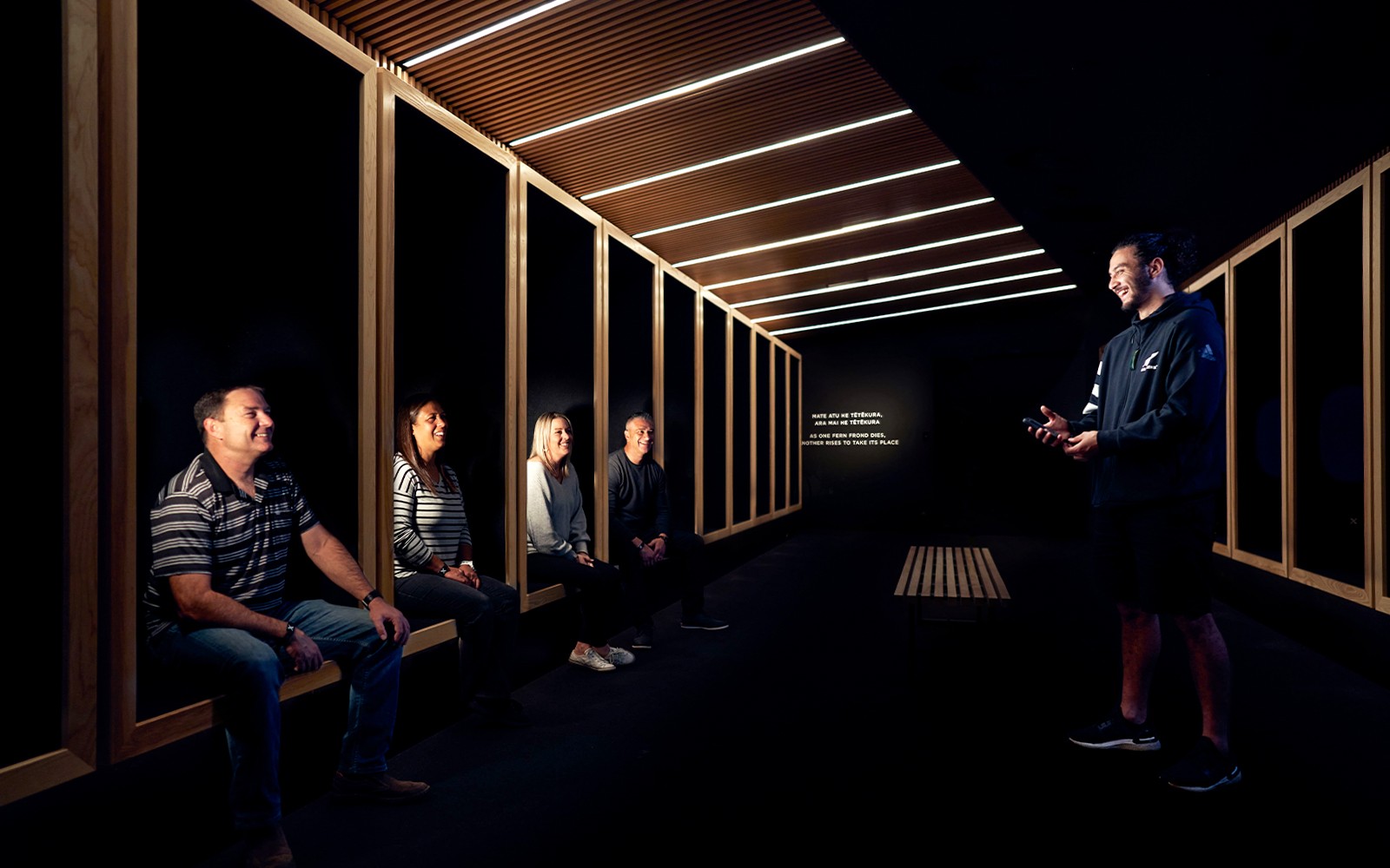 Visitors seated in a dark room listening to a guide at the All Blacks Experience in New Zealand.