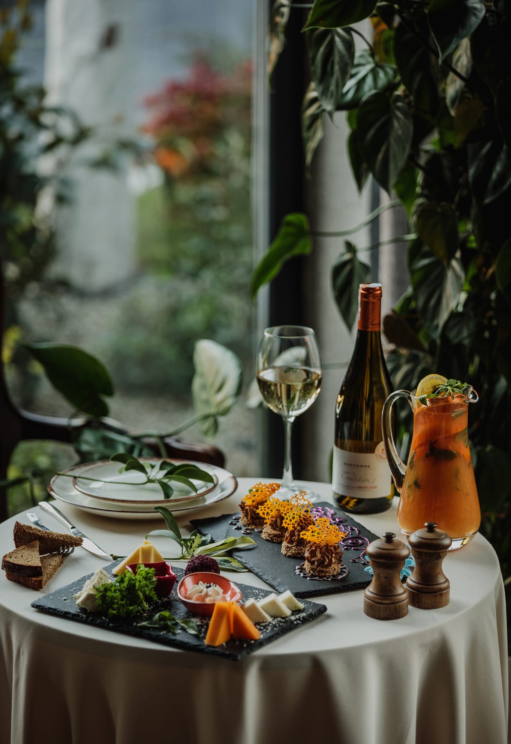 a red drink sitting on top of a table next to a potted plant