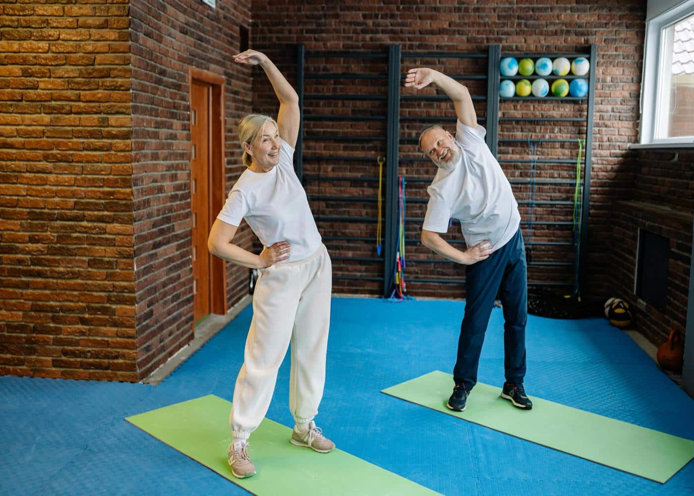Older couple standing on yoga mats stretching