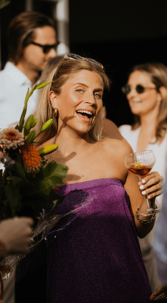 Close-up portrait of a person wearing a gray insulated hooded jacket with the hood up, showing their face framed by the hood against a light background.