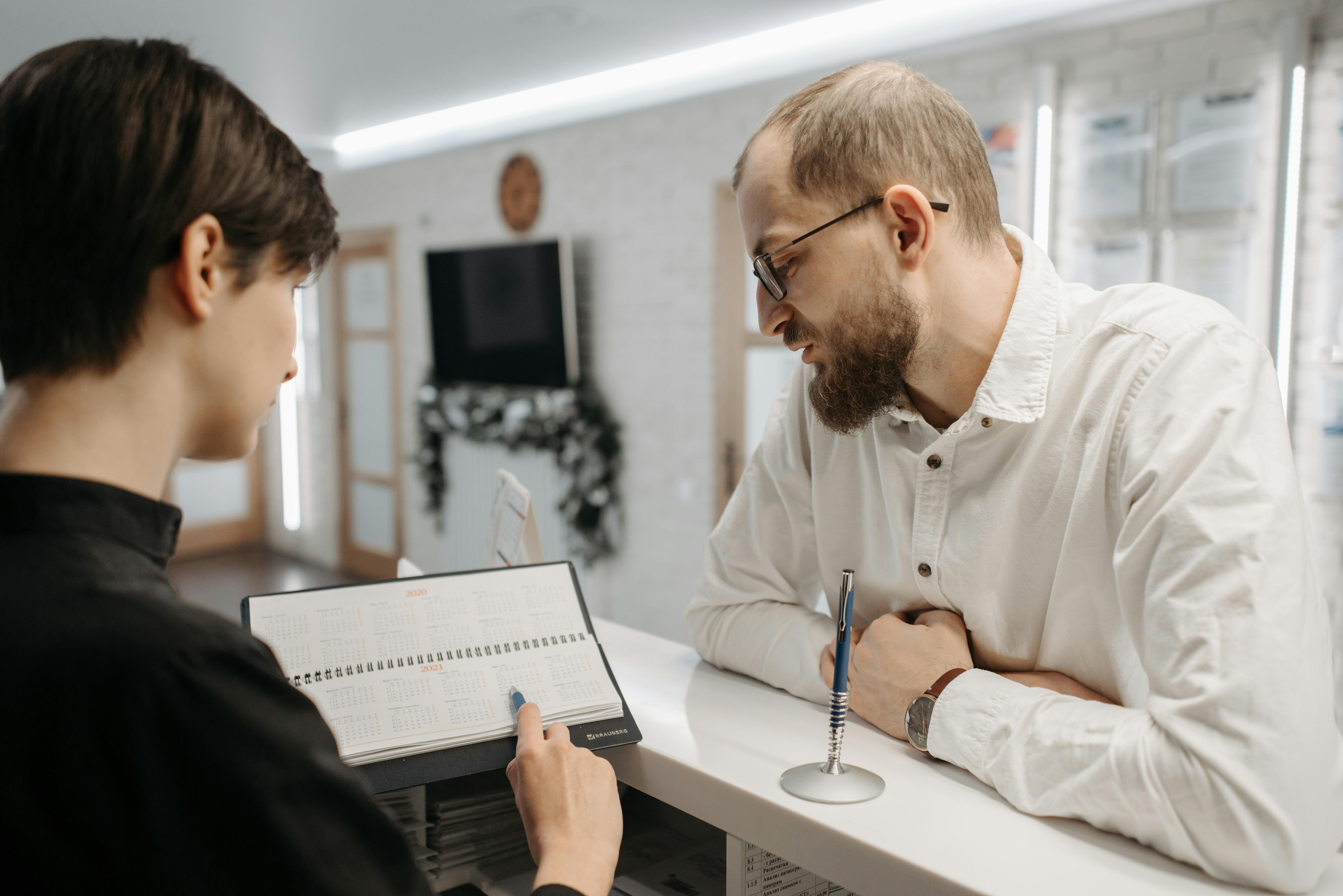 woman explaining something to man at front desk of dental office