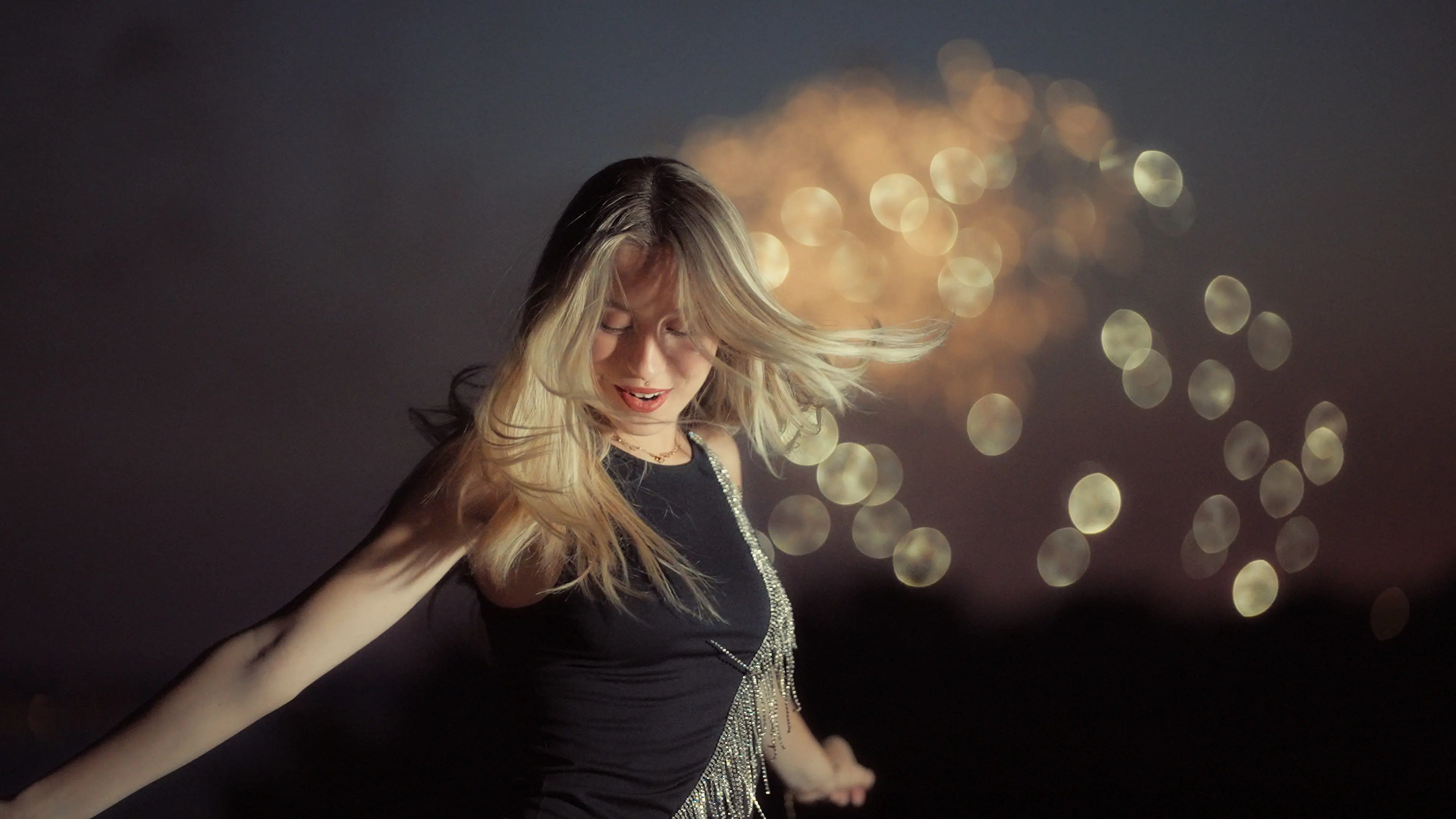 A woman twirls in a twilight setting, with sparkling  fireworks in the background.