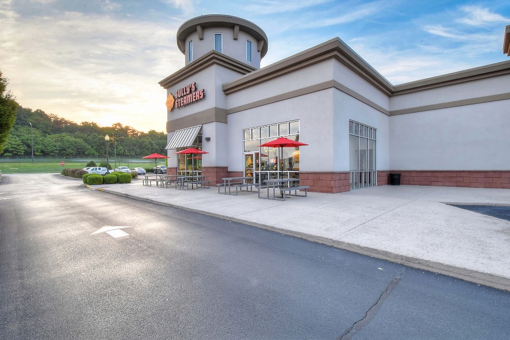 A modern building with a round tower, surrounded by green grass and a clear sky in the background.