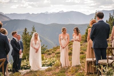 Two guests stand facing the couple during the outdoor ceremony.