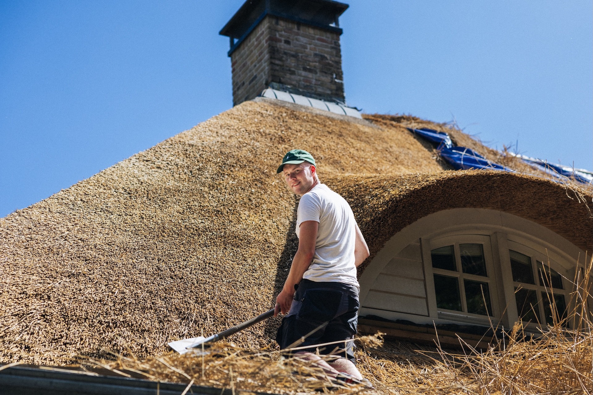 Rietdekker op het dak aan het werk van Rietdekkersbedrijf van Dijk