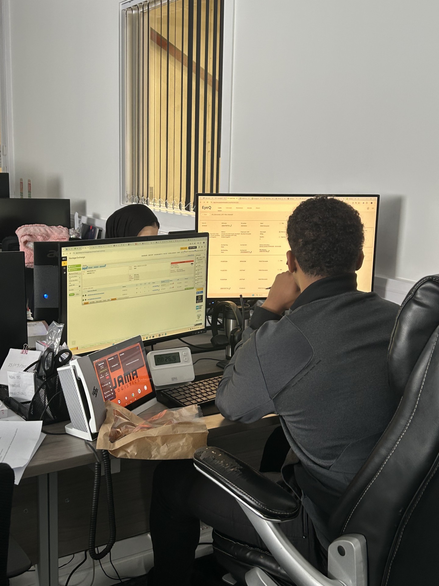 image of the back of a mans head in an offcie looking at two monitors doing logistics workl
