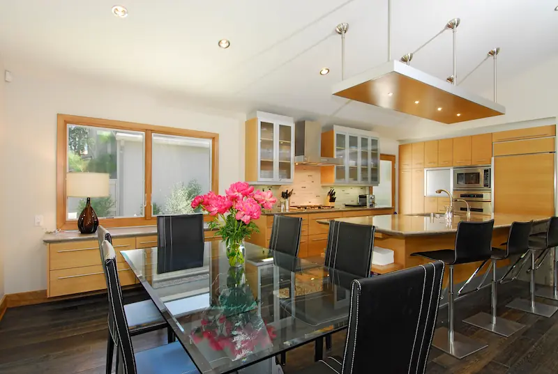 Modern kitchen with wood cabinets and glass dining table, vibrant flowers. Photo by Chris Darnall for Irvine Transitional Modern Project. Photo by Chris Darnall.