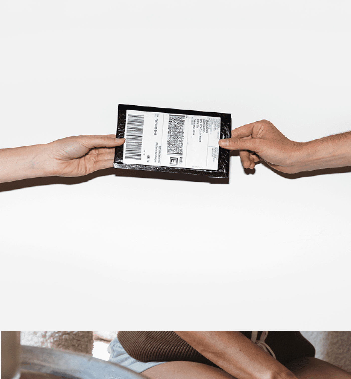 Hands passing a Rythm test kit package from one person to another.