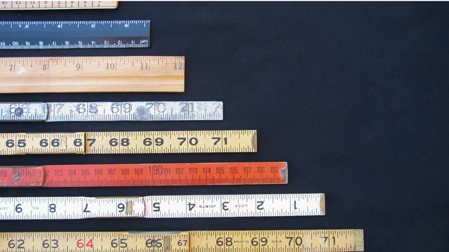 Various measuring rulers arranged diagonally on a dark surface, symbolizing metrics and measurement.