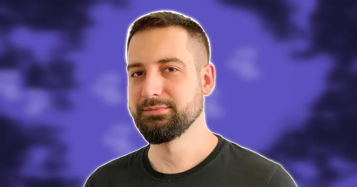 Portrait of Lucas Ostrowski, automation expert and founder of Acutus Digital. Bearded man with short dark hair wearing a black t-shirt, looking confidently at camera. Purple background symbolizes innovation in AI and no-code solutions for B2B automation.