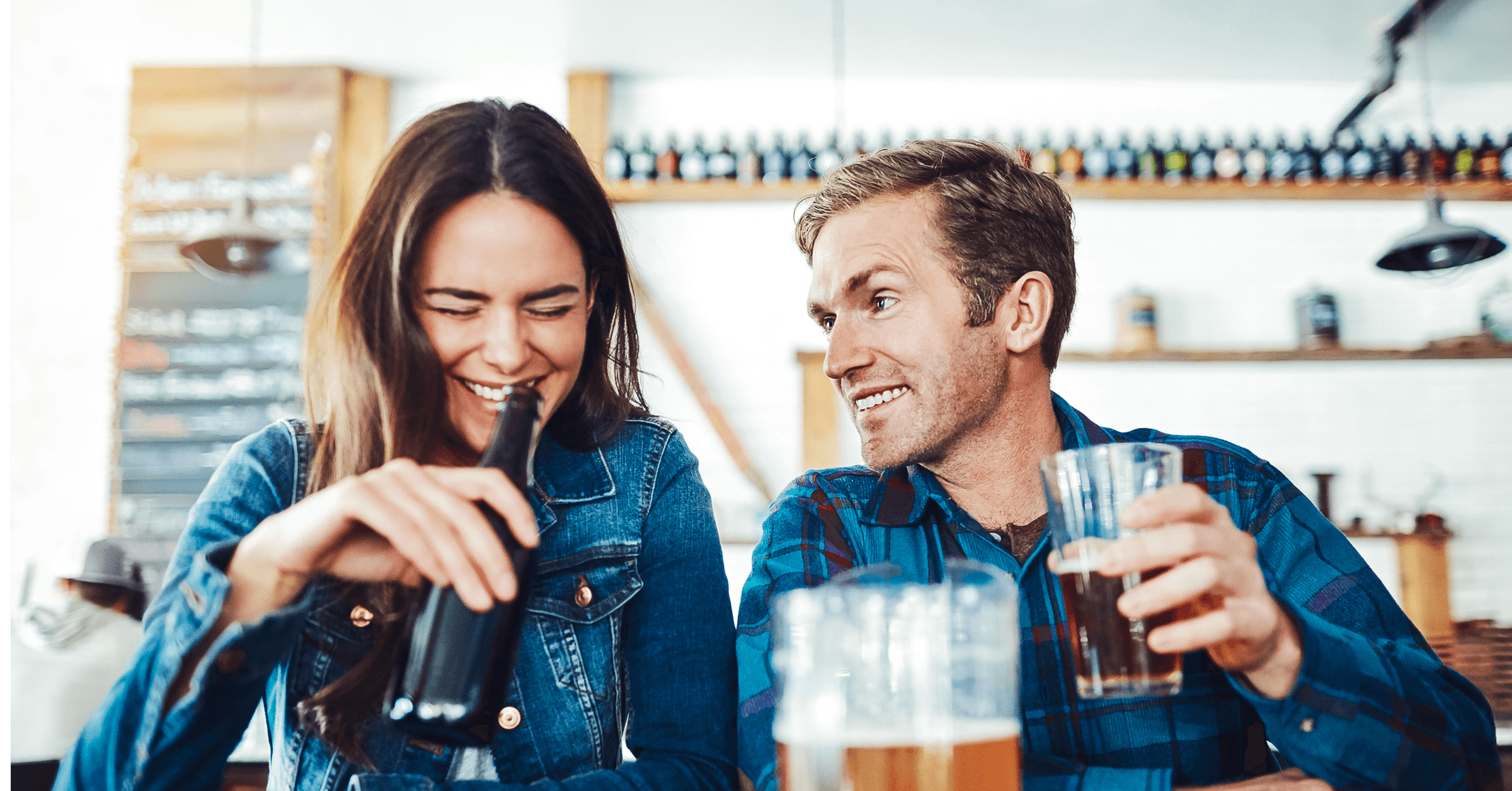 En mann og kvinne er på date på en bar. De ler og nyter hverandres selskap mens de drikker øl.