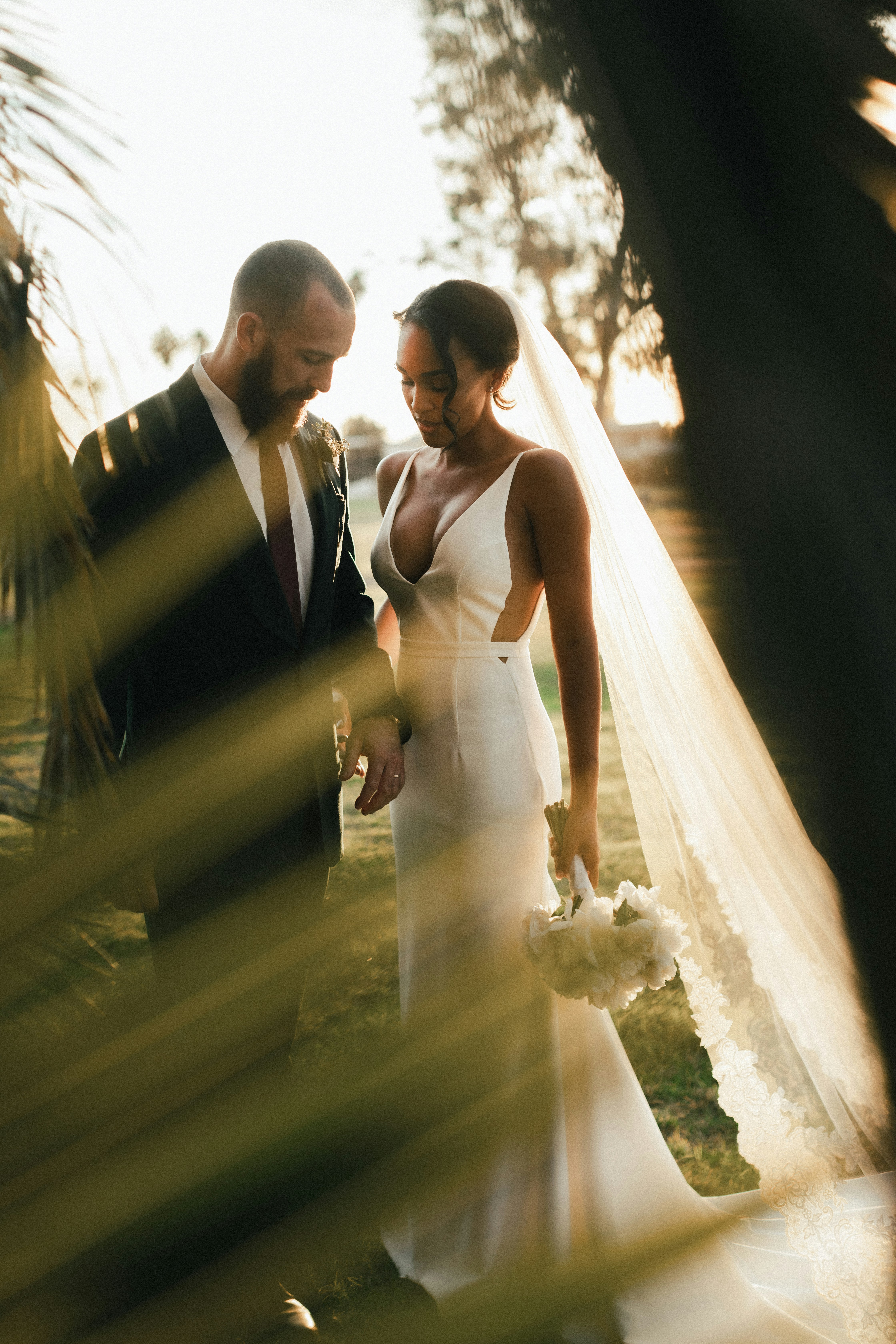 A bride and groom share a kiss surrounded by a joyful bridal party.