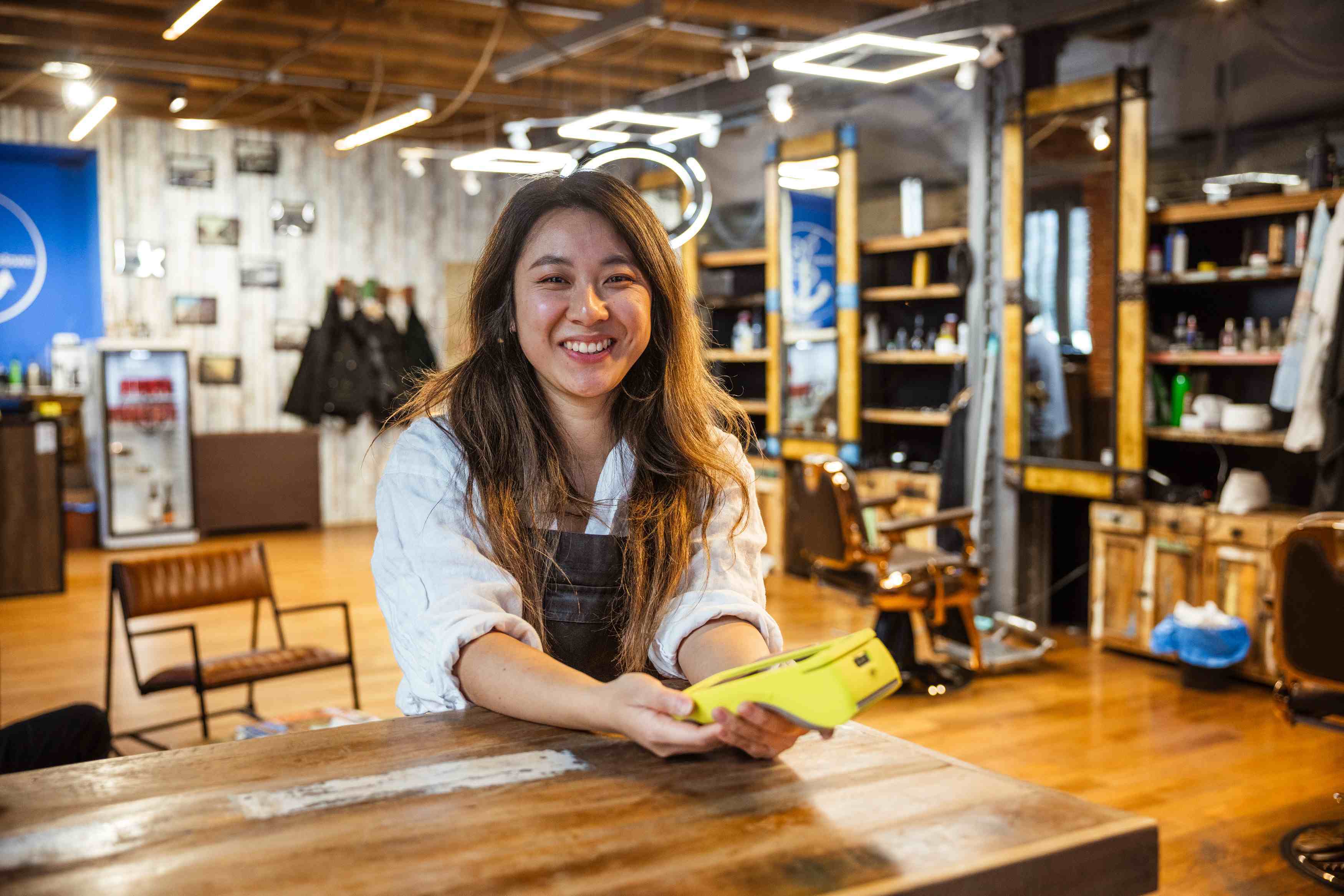 a barber shop owner holds a Teya card machine on her desk