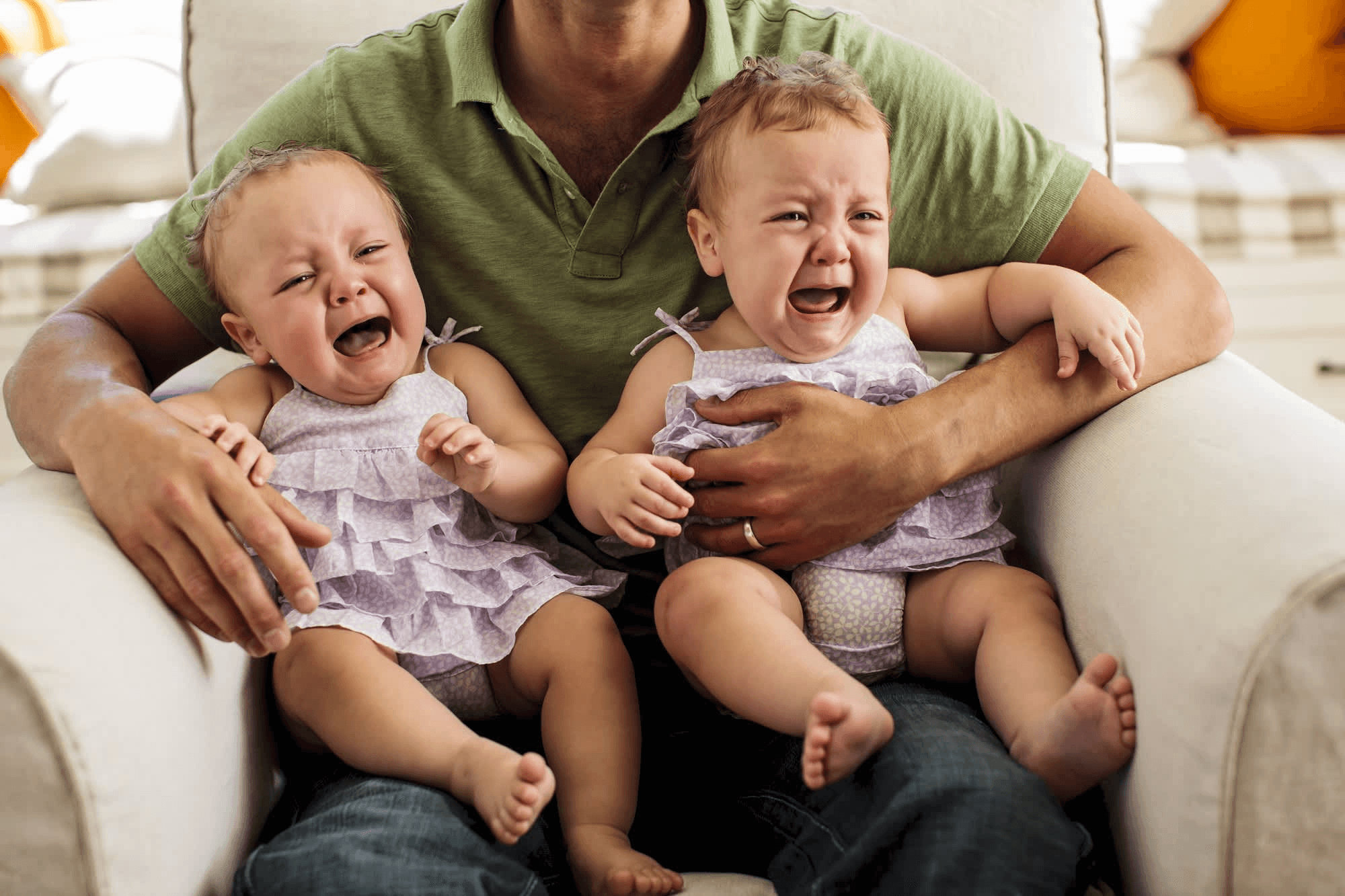 Father holding twin crying babies on his lap, representing parenting challenges