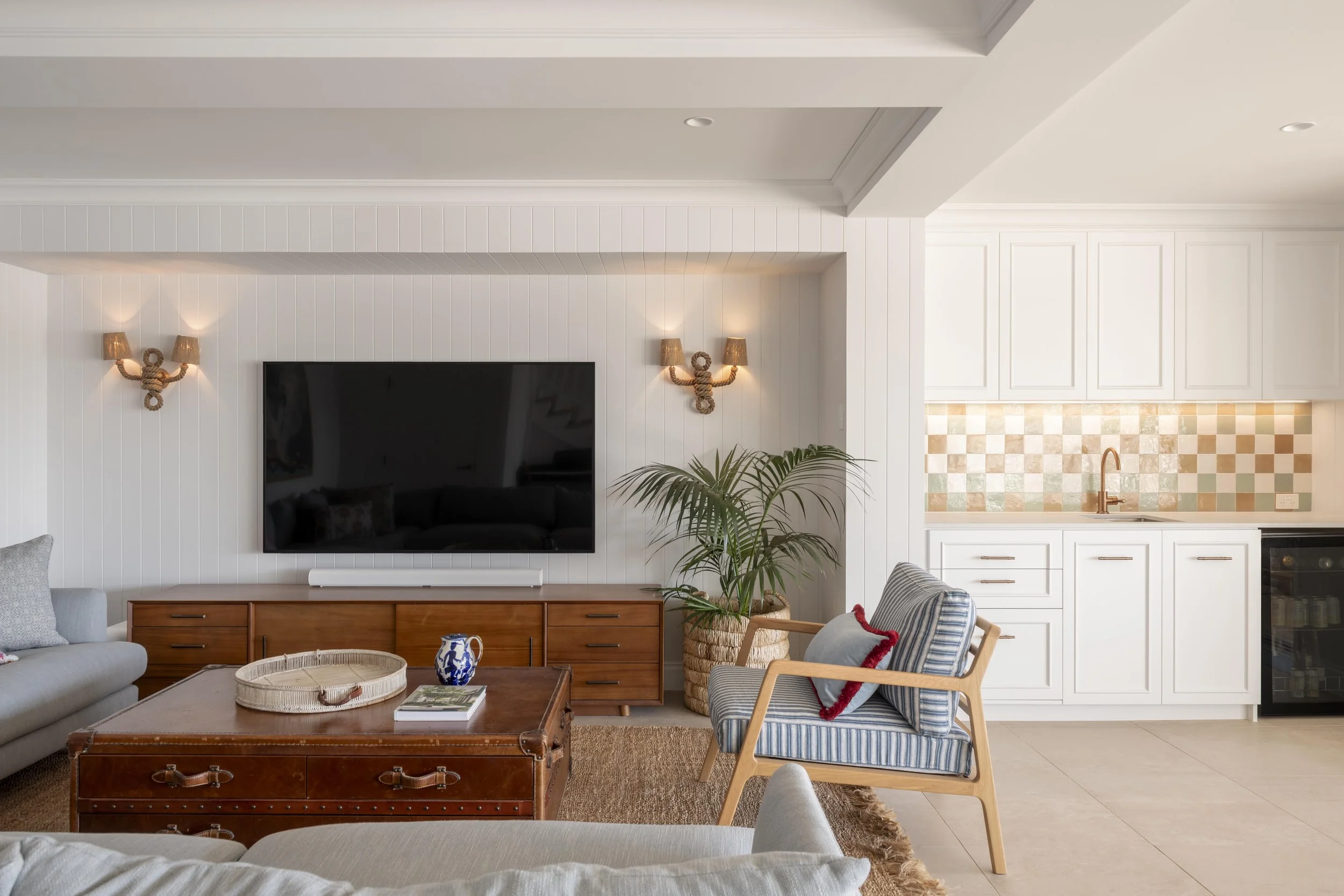 Living room with built-in TV wall, timber cabinetry, and adjacent kitchenette.