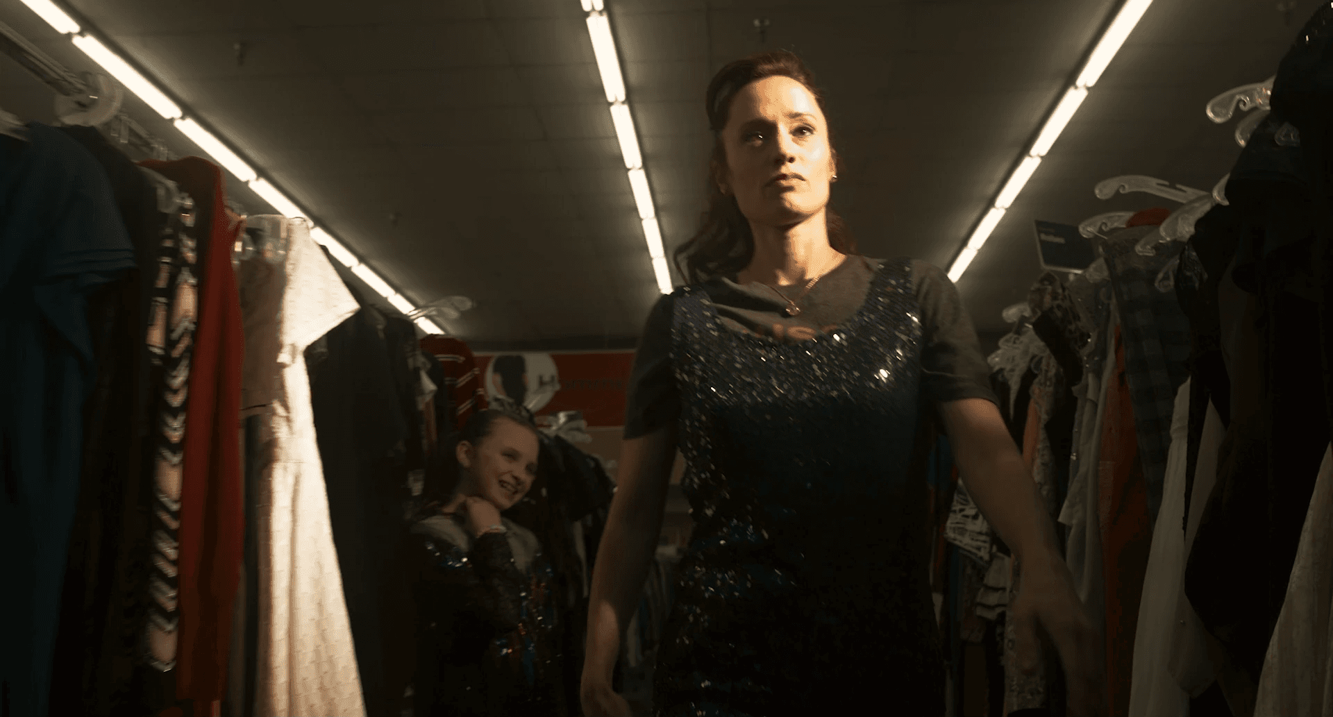 Une femme et sa fille en robe a paillettes dans une loge.