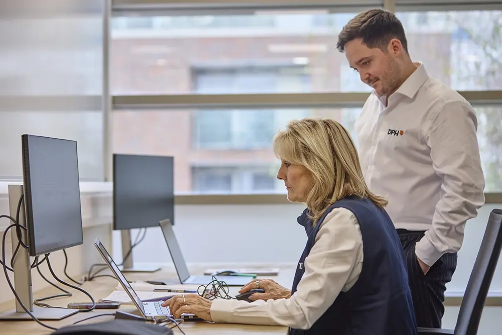 Entrance of a modern glass building with illuminated facade and reflections