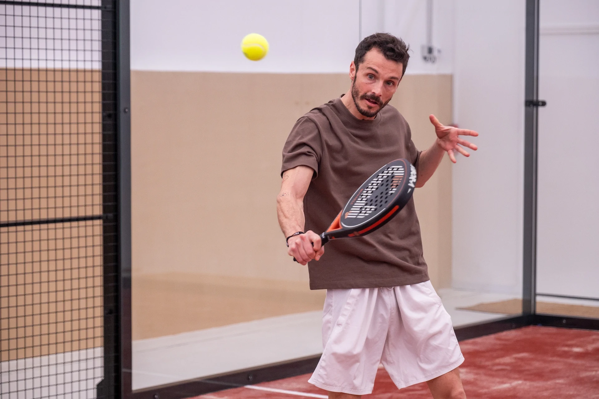 Joueur de padel en action. Service de padel en salle.