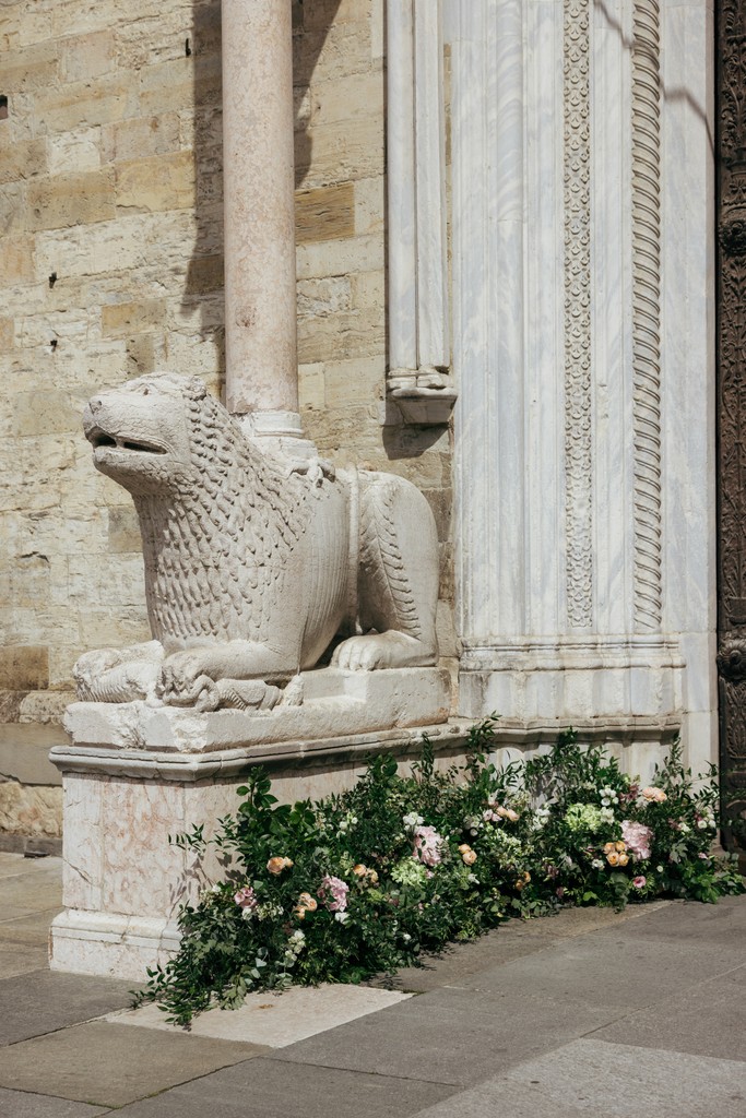 Dettaglio architettonico con scultura in pietra e fioriture bianche davanti a villa per matrimonio
