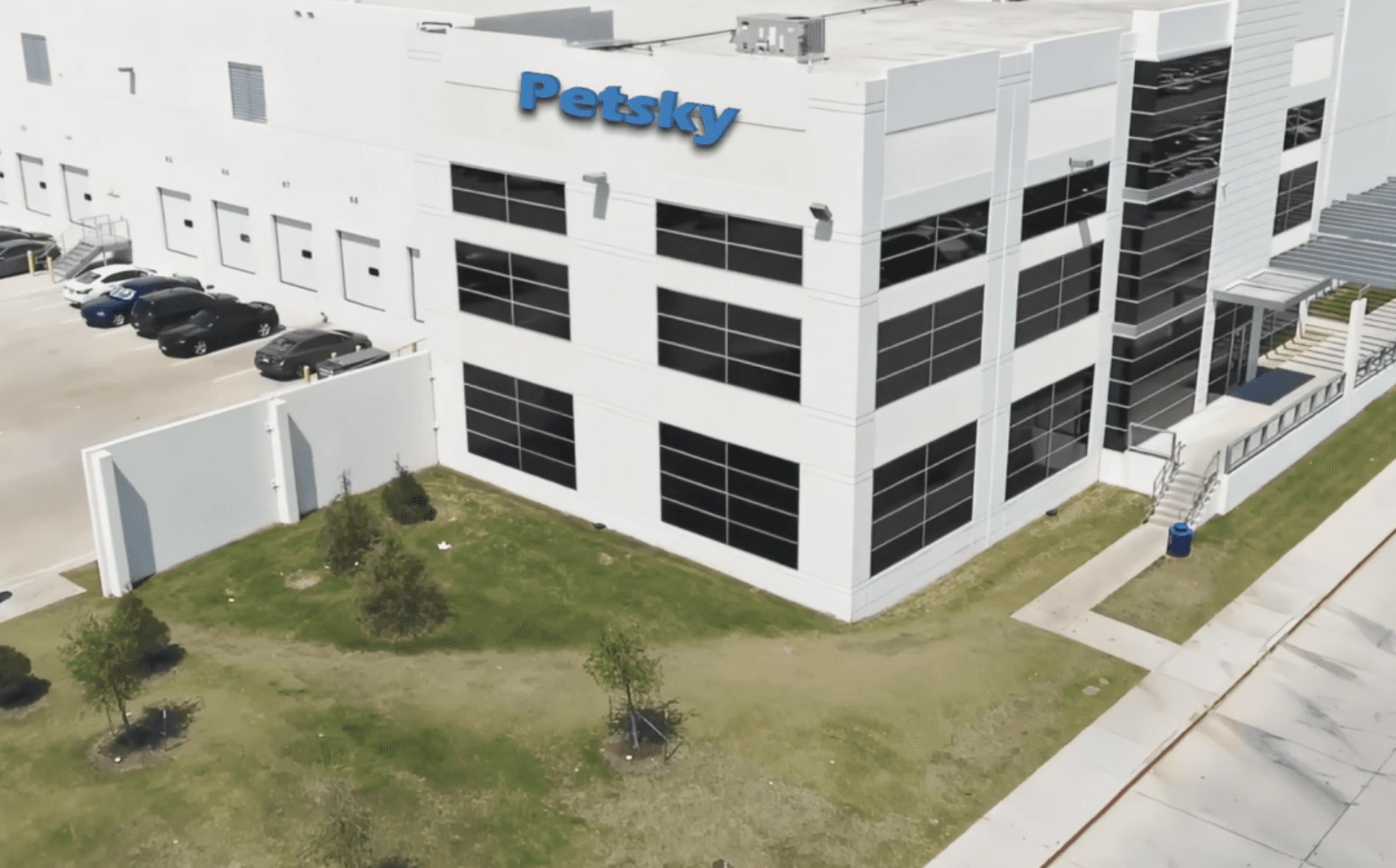 An image of a white building with "Petsky" labeled at the top. There is a parking area with cars.