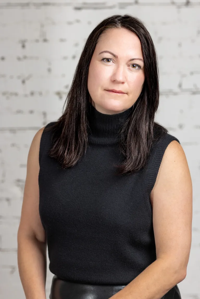 Image of Woman standing confidently in front of brick wall, representing KHD Homes' design and construction expertise.