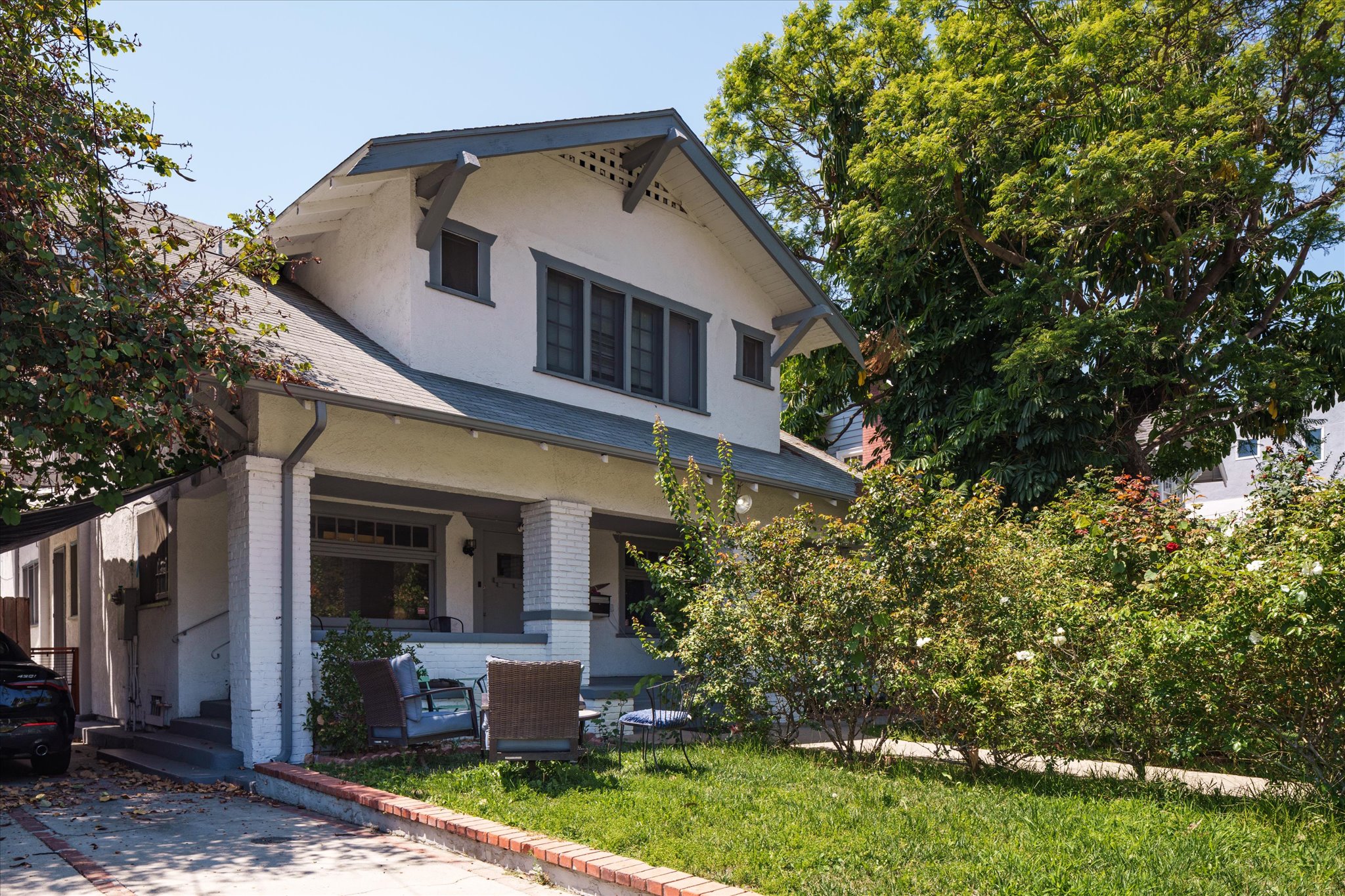 A two-story house at 1807 n van ness ave, with a porch, surrounded by greenery and trees under a clear blue sky.