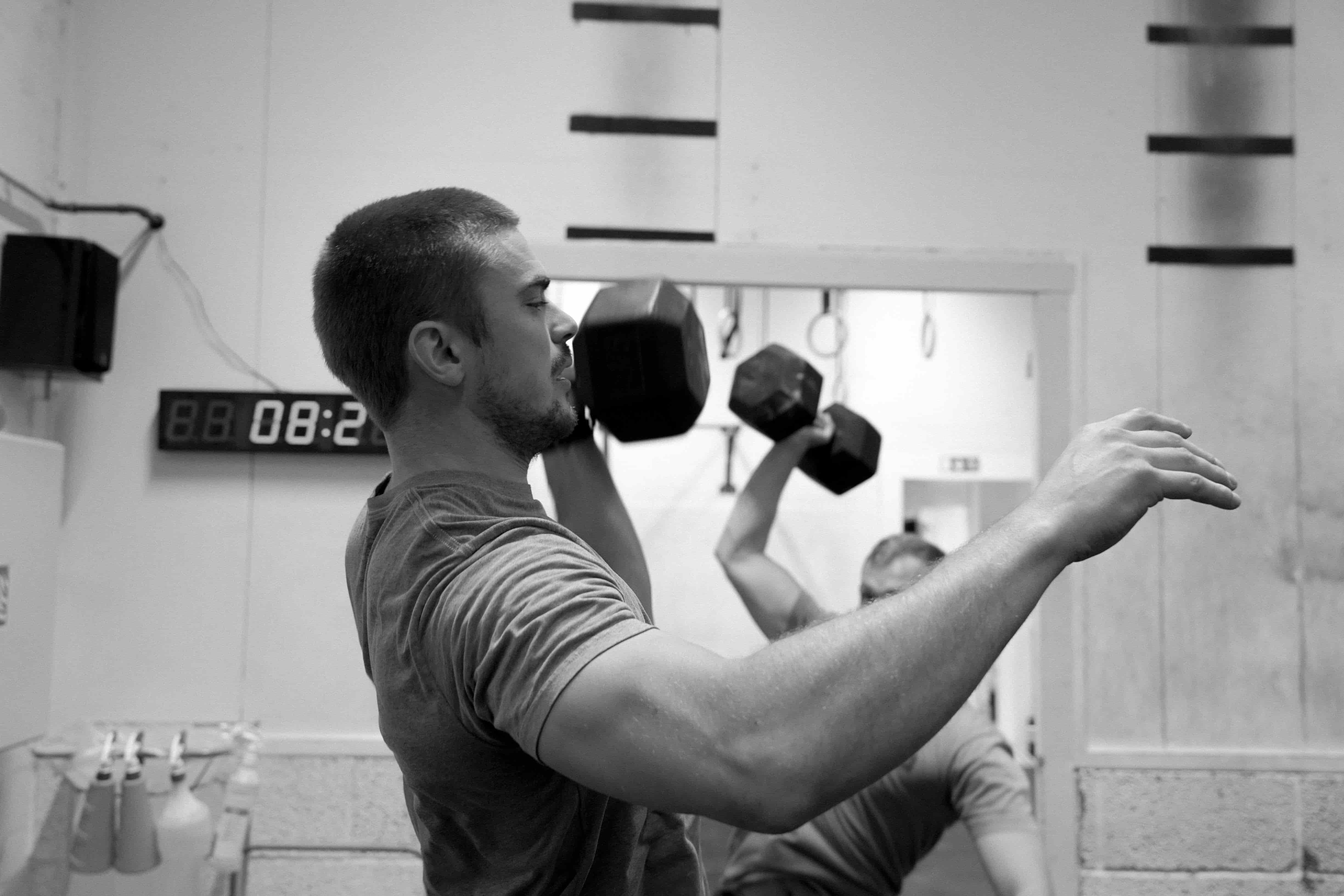 To personer løfter en dumbbell over hodet