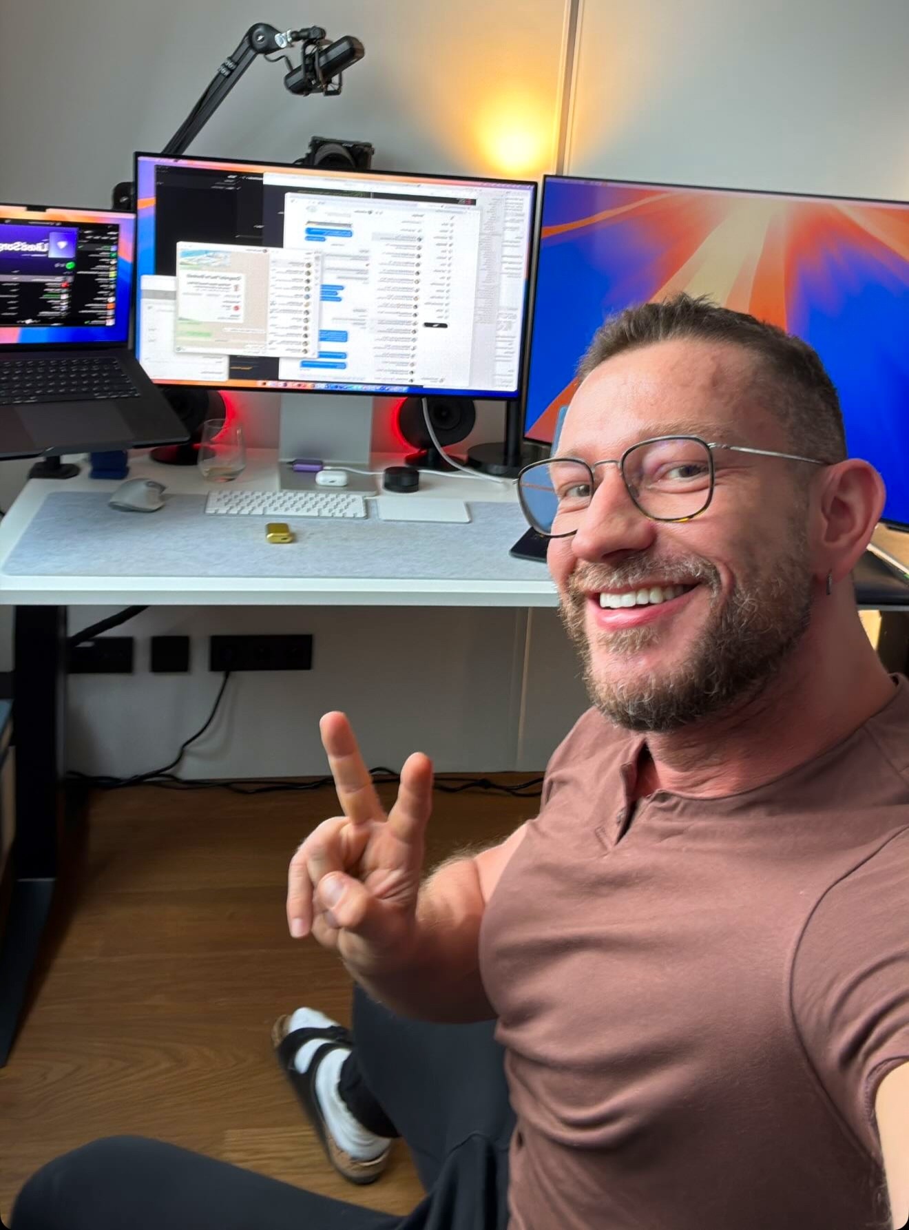 a man with his arms crossed standing in front of a desk