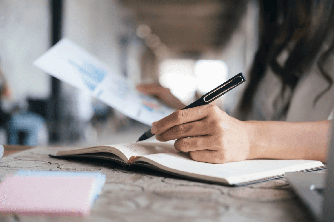 a person holding a graph in one hand and a pen in the other while writing in a workbook