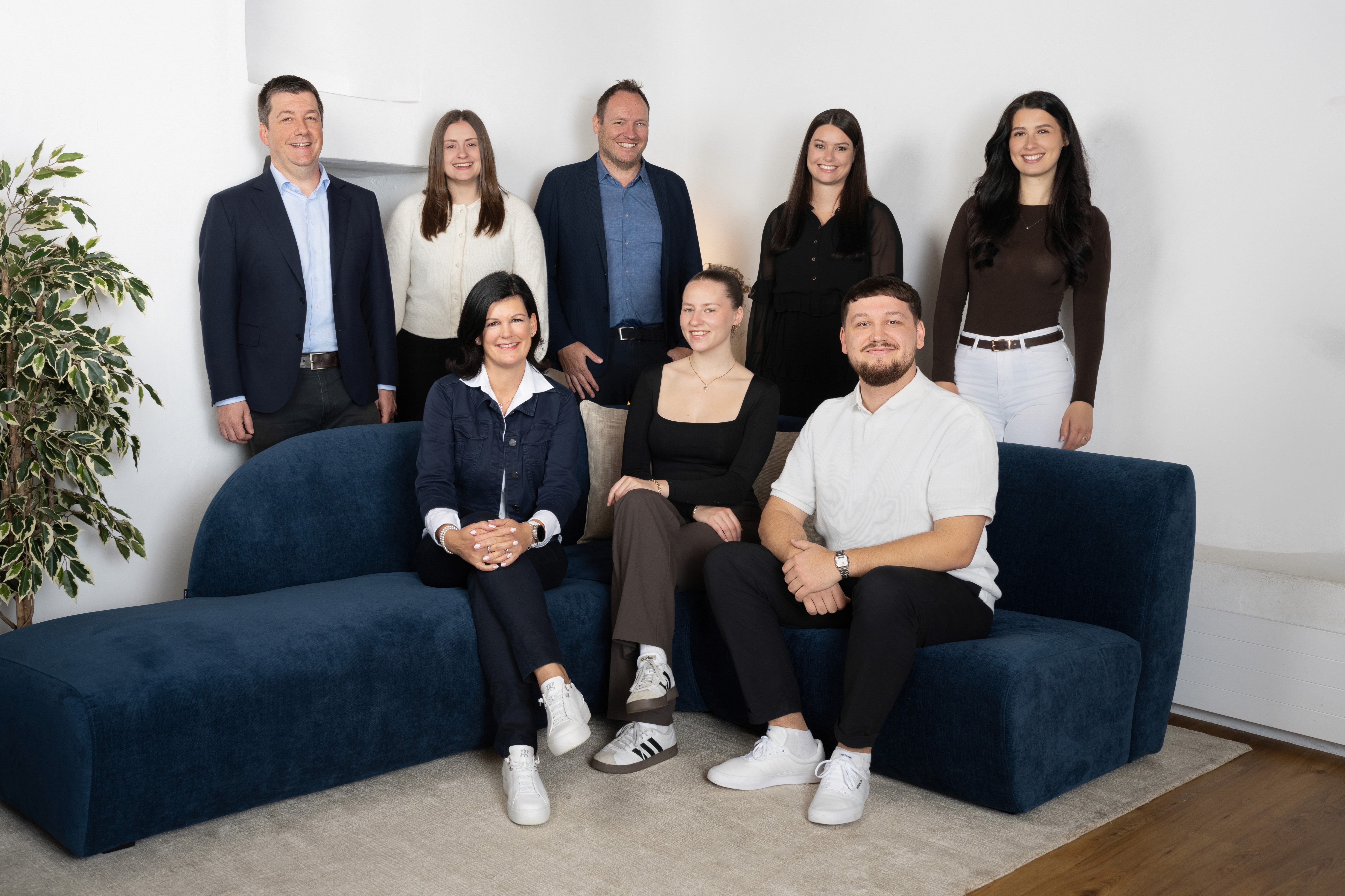 Team von Kocher Immobilien sitzt auf Treppe vor Gebäude und posiert gemeinsam