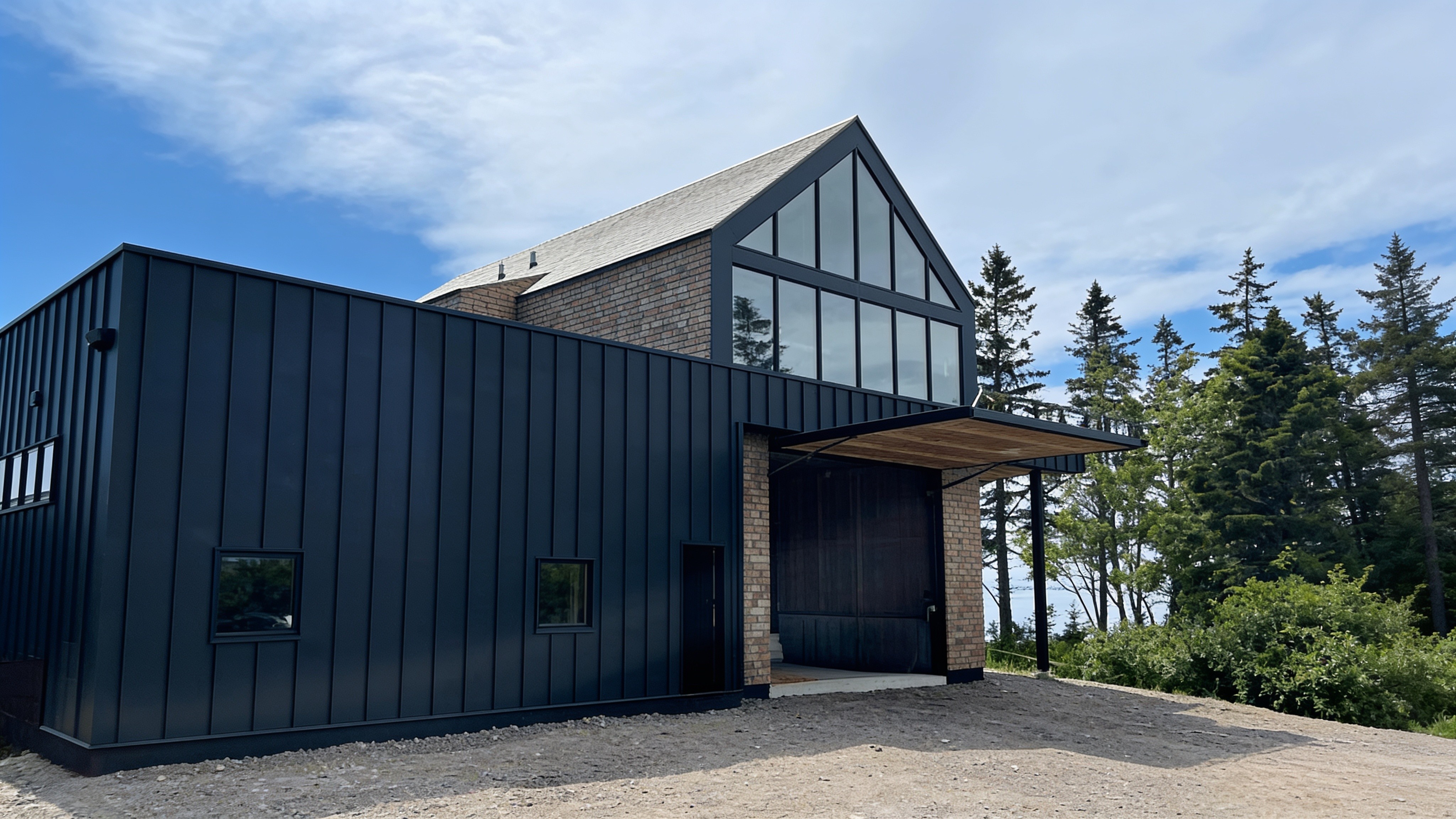 Architectural boat shed with an open hydraulic door and gravel drive