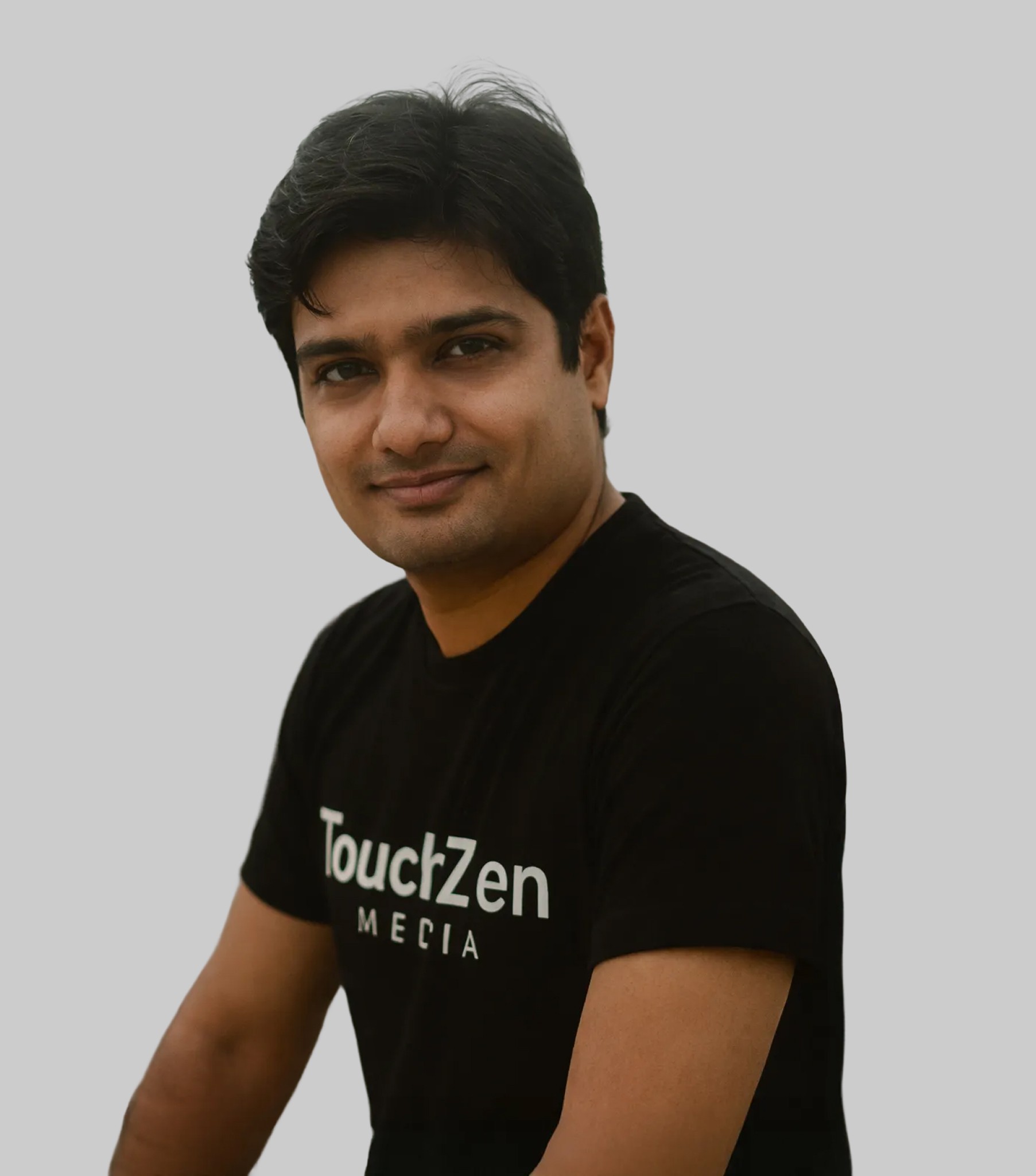 A young man in a white t-shirt stands against a light-colored background.