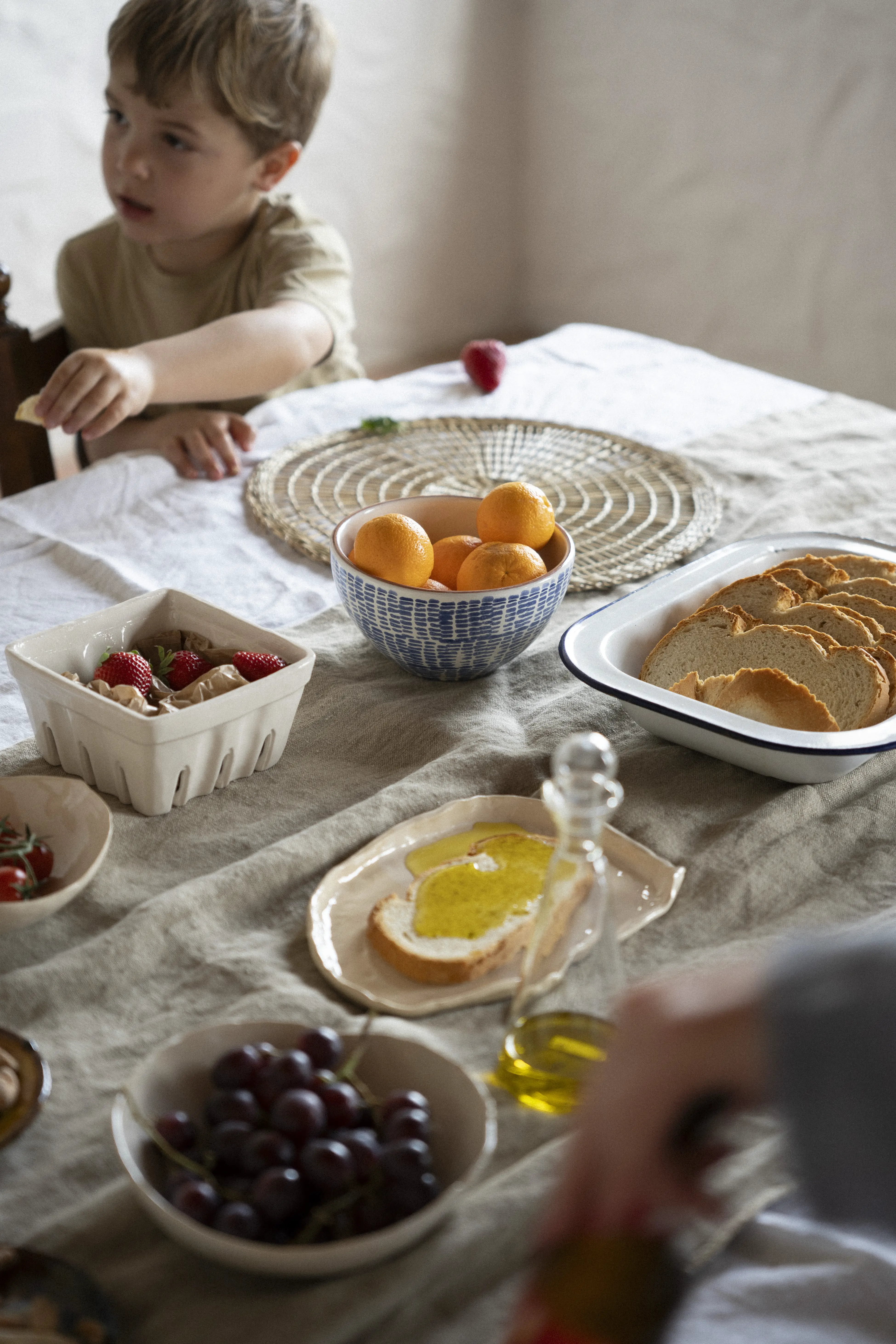 niño en una mesa llena de cuencos con frutas variadas