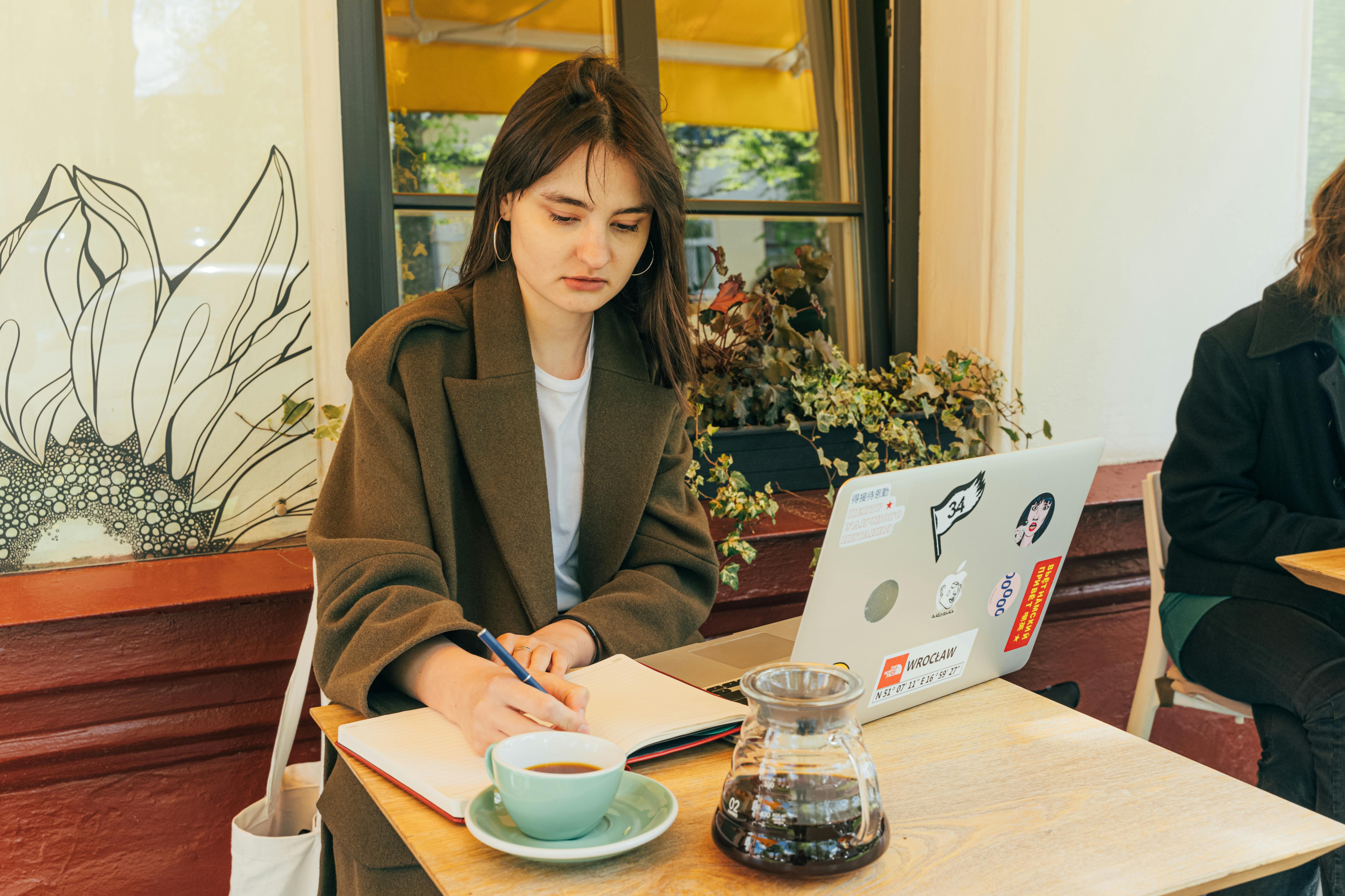 seorang perempuan sedang menulis buku di atas meja